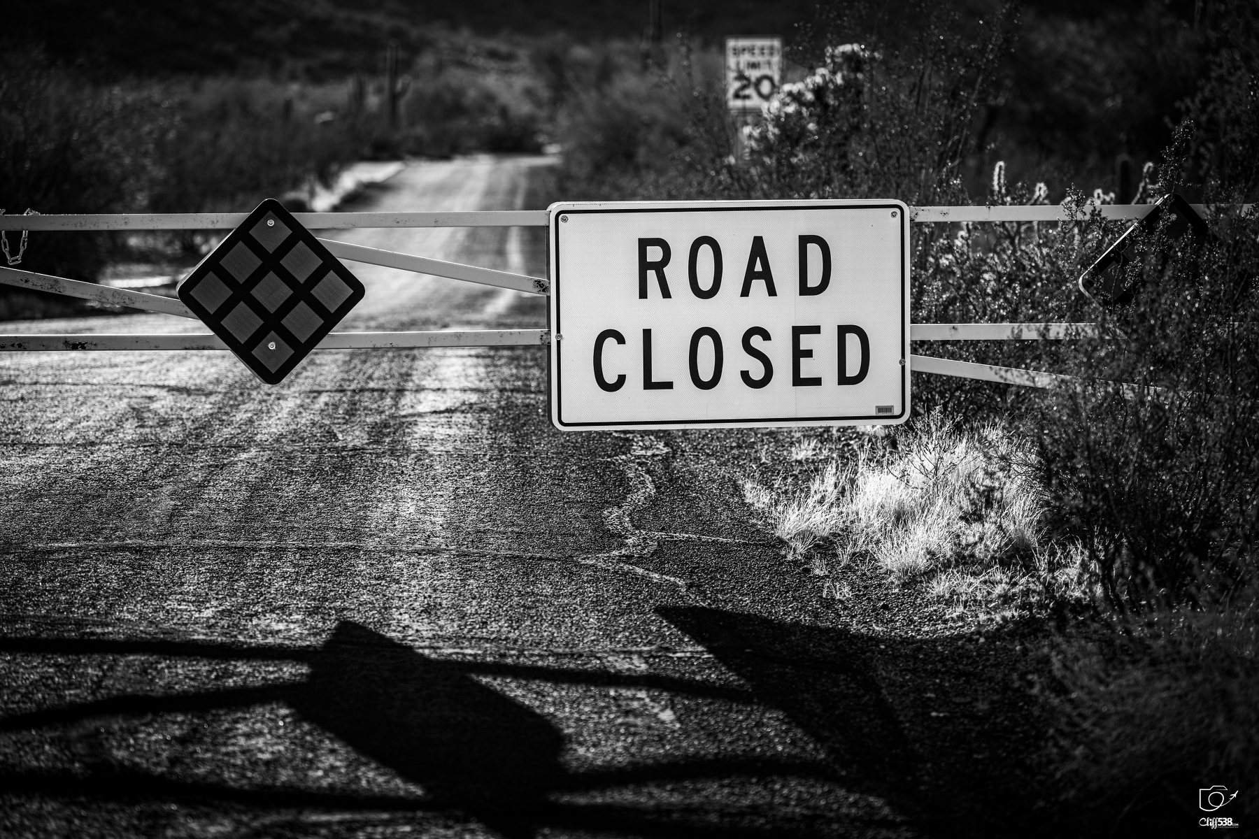 Auto-generated description: A road is blocked by a gate featuring a ROAD CLOSED sign, indicating that passage is not allowed.
