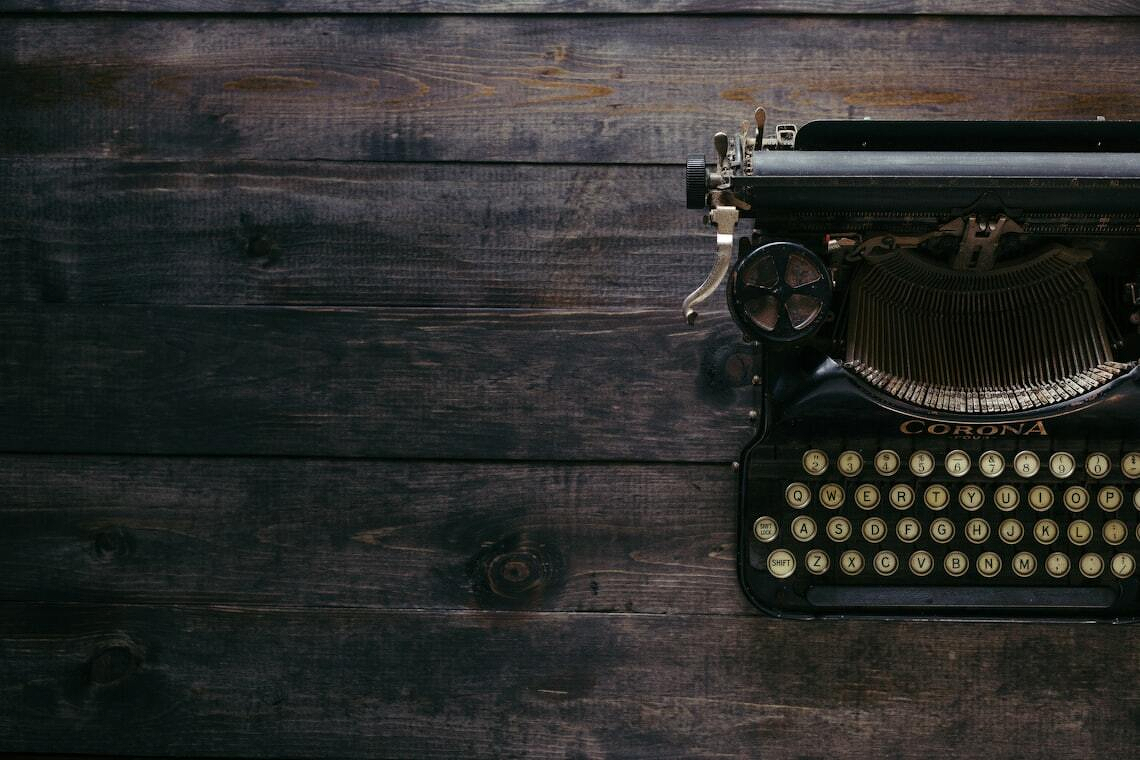 A vintage typewriter sits on a dark wooden surface