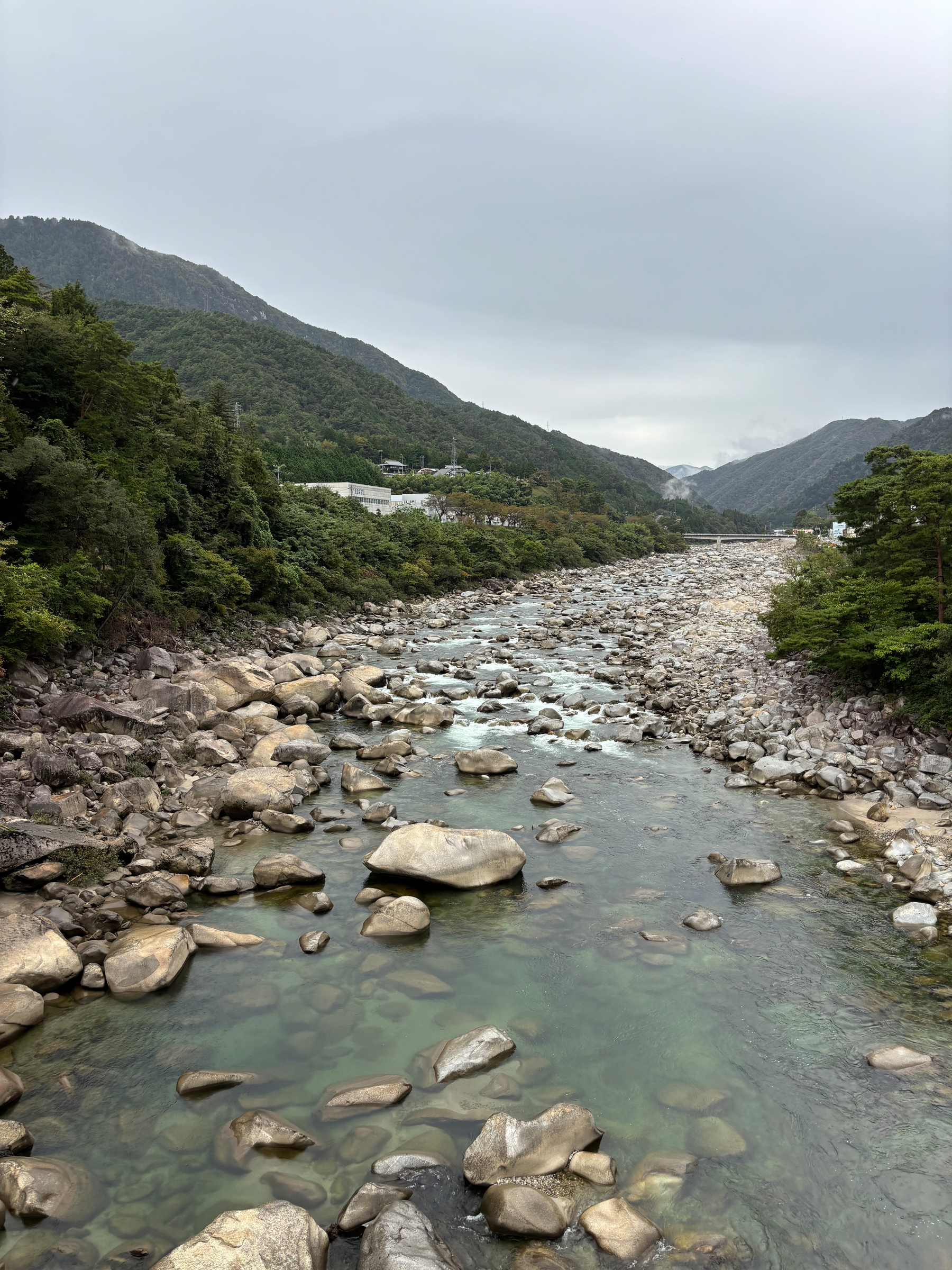 View of a rocky river in Nagiso, Nagano, that winds up to the misty mountains.