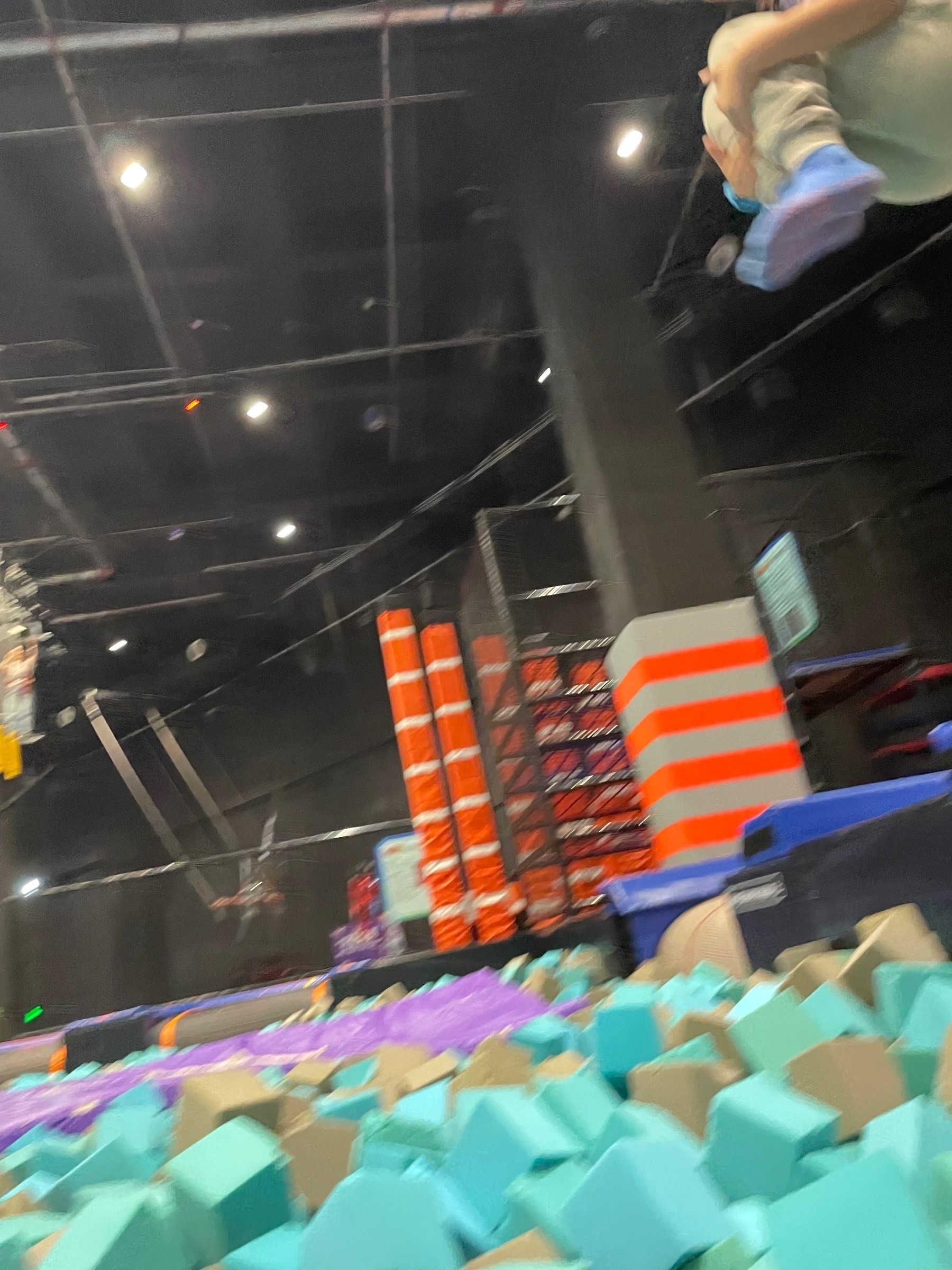 Girl jumping into a foam pit, only her feet are visible.