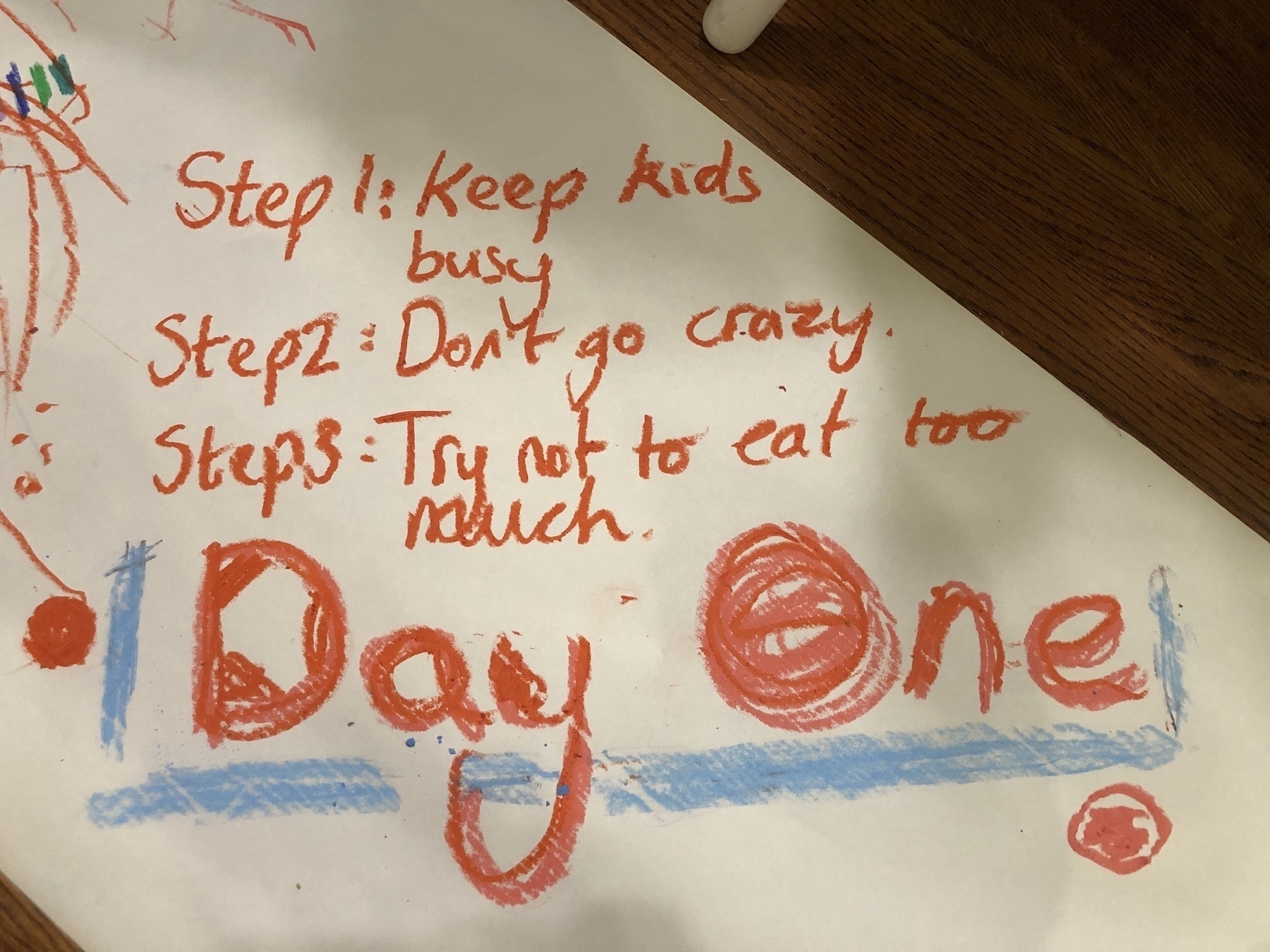 A piece of paper with a handwritten list titled "Day One," including three humorous steps: "Keep kids busy," "Don't go crazy," and "Try not to eat too much," written in red and blue marker.