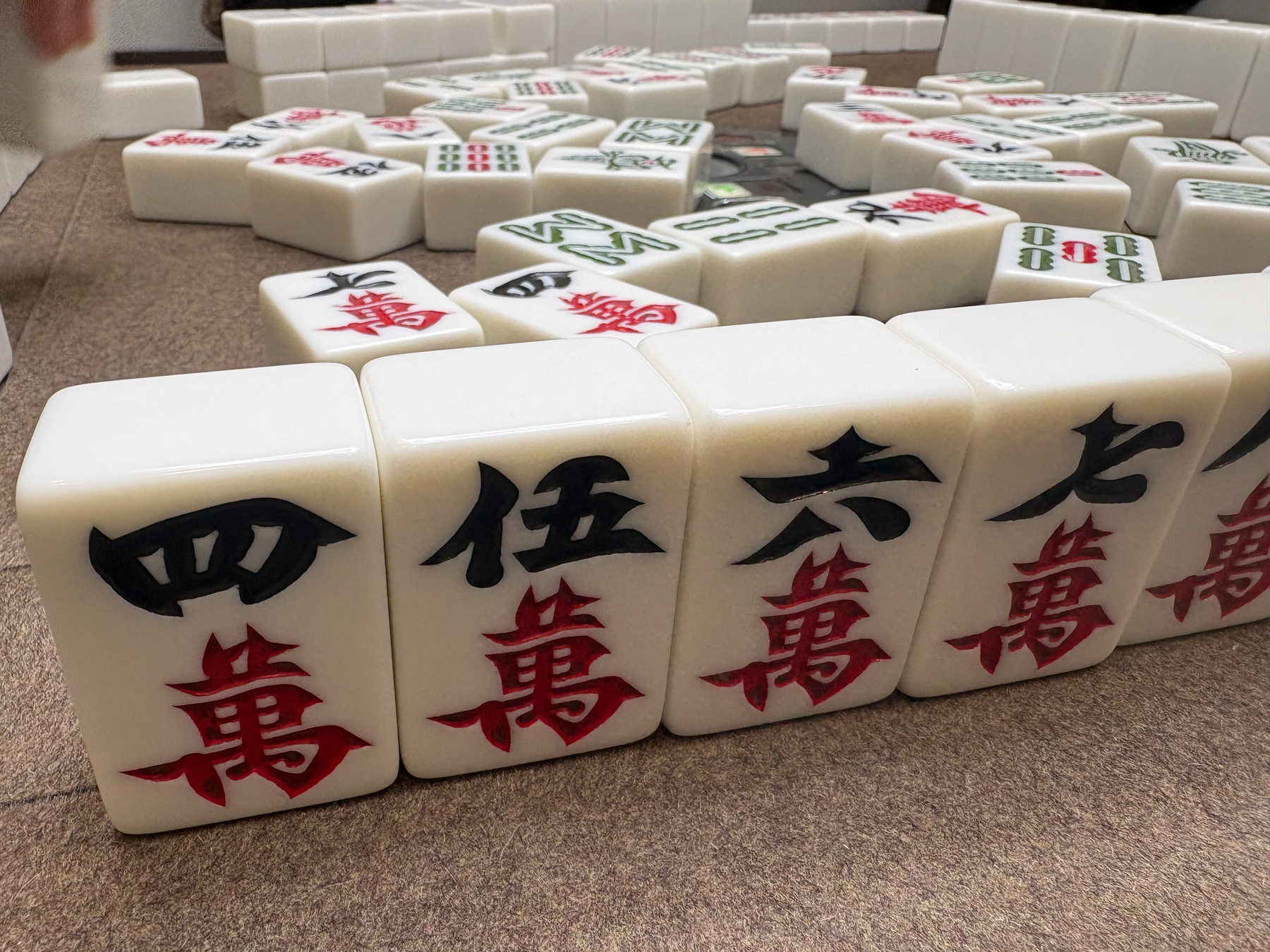 Mahjong tiles with Chinese characters and numbers are arranged on a felt-covered table.