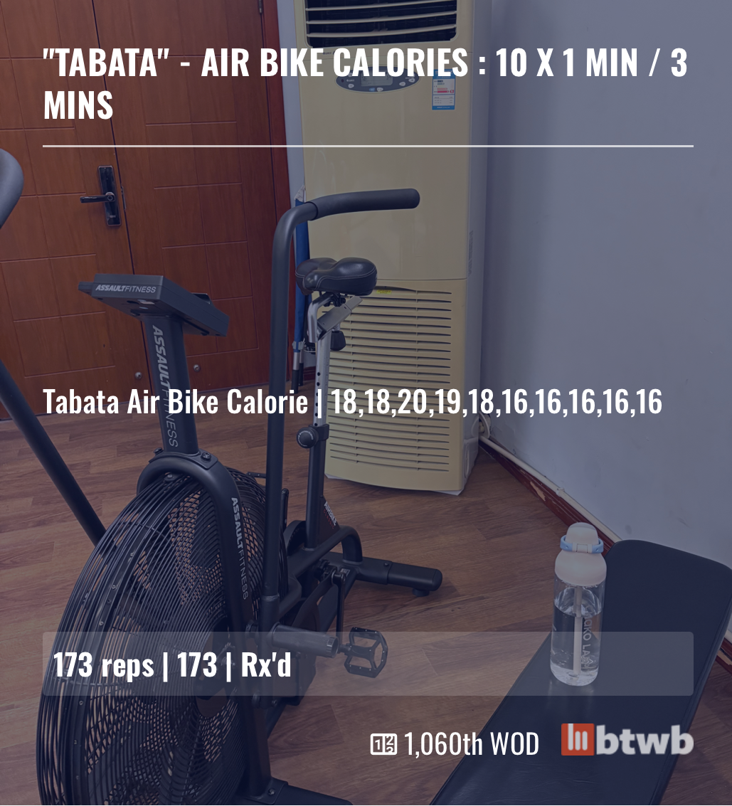 An air bike is set up in a room next to a bench with a water bottle, displaying a workout summary for a Tabata air bike calorie session including reps and calories burned per minute.