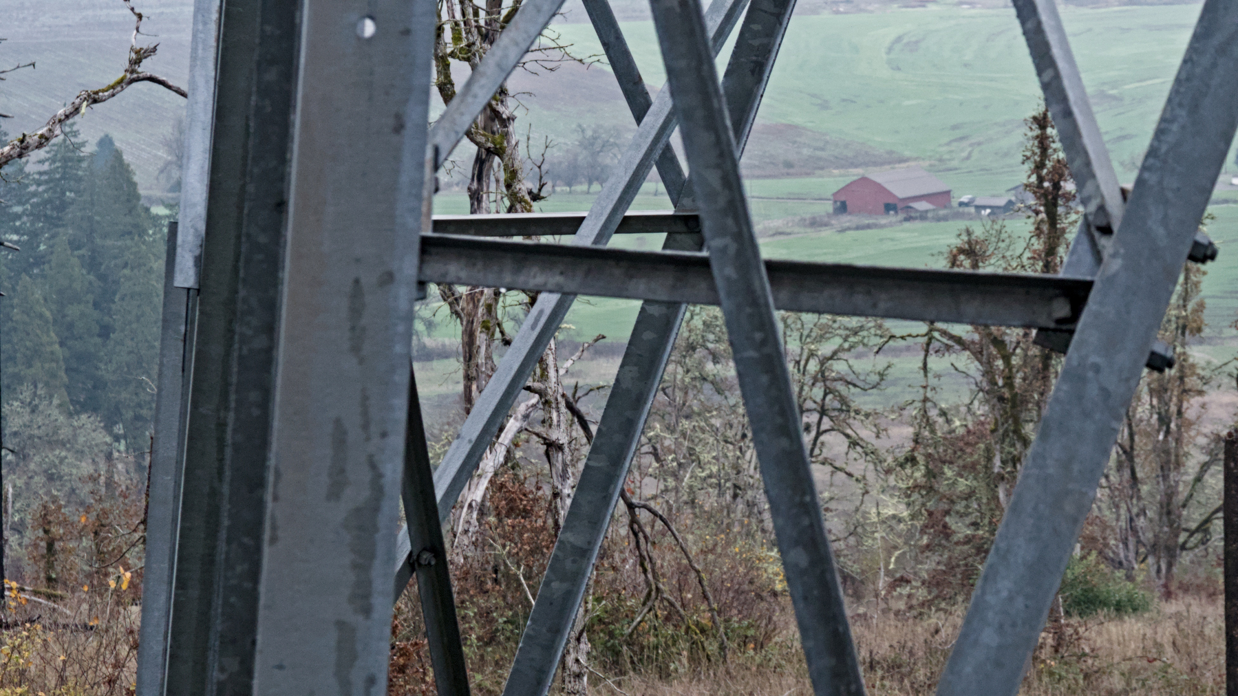 barn framed by girders of a pylon