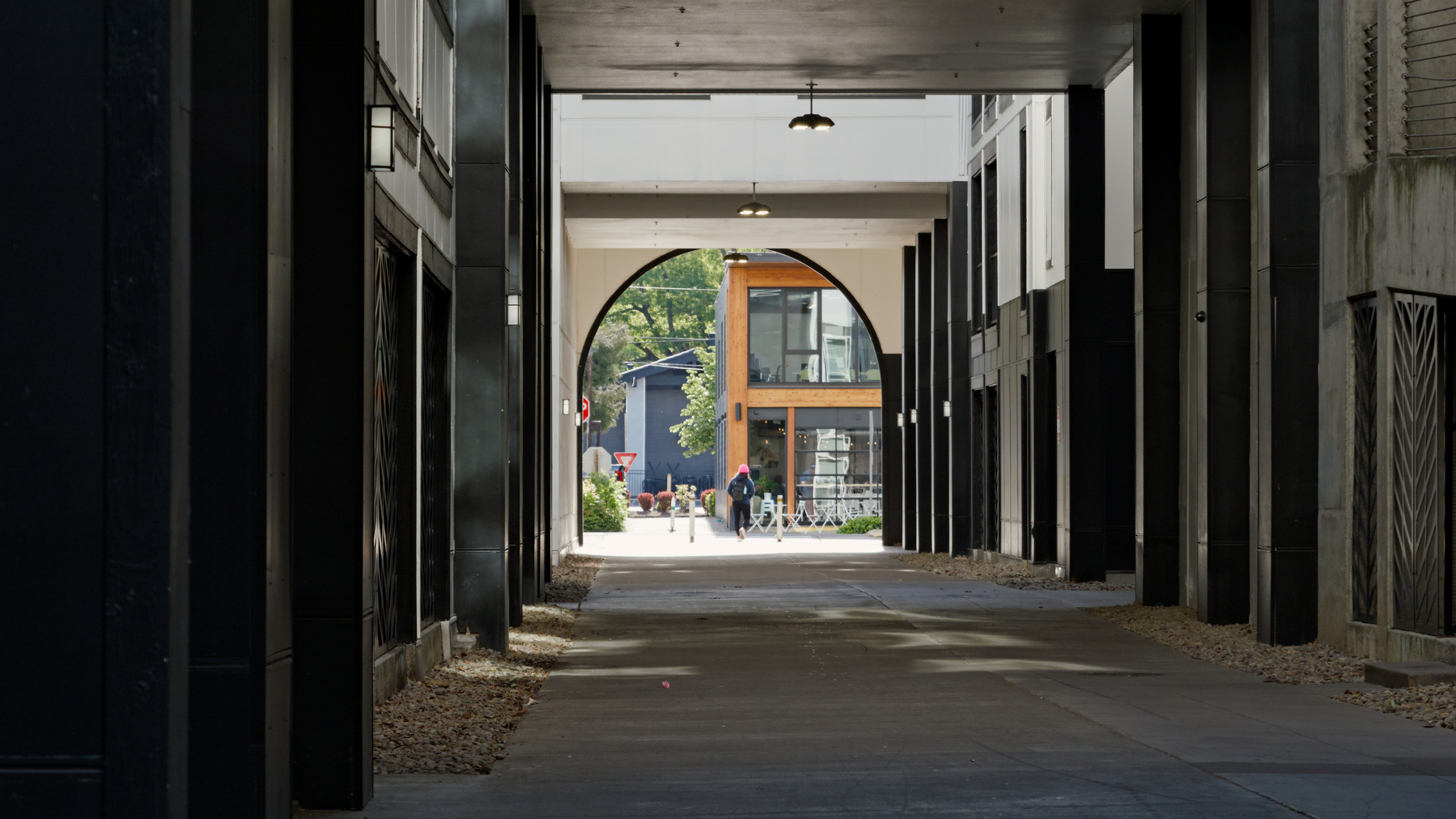 person walking from a dark alley into a light street