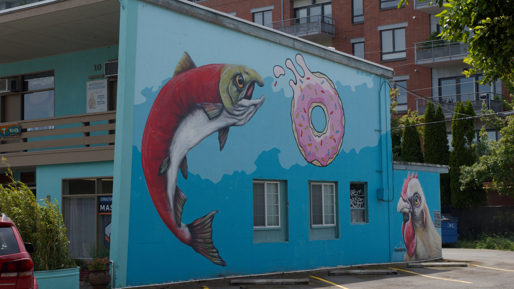 salmon, donut, and rooster painted on the side of a building