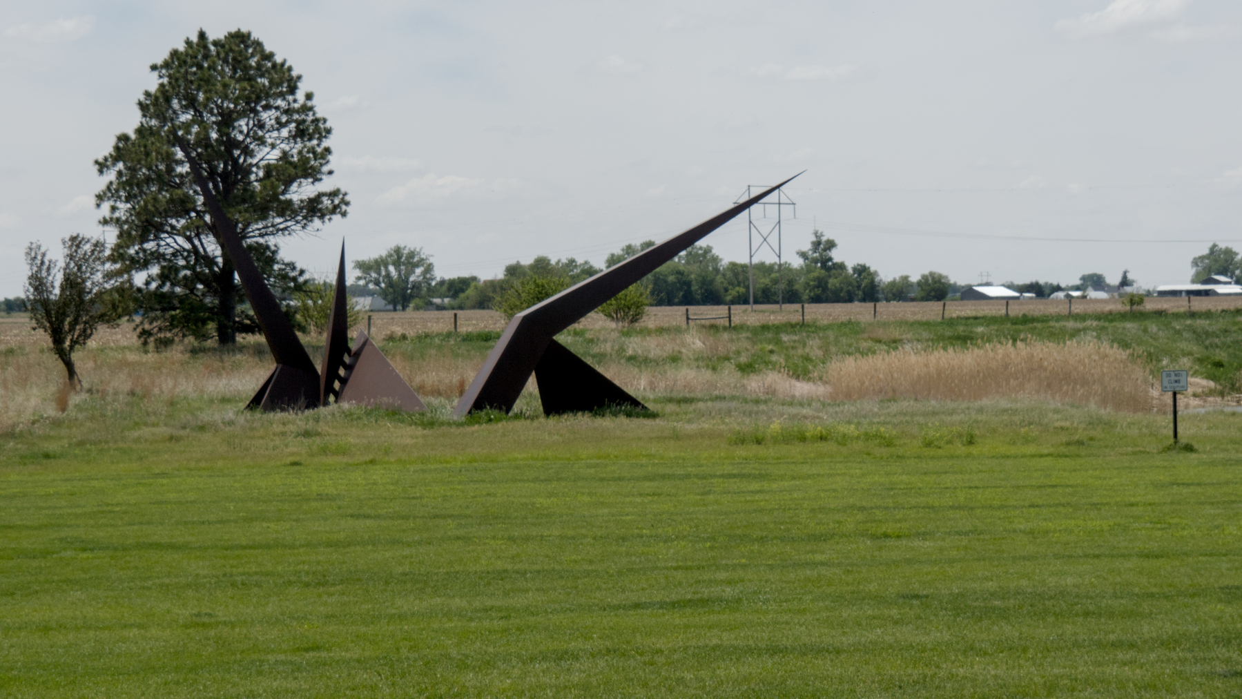 angular steel sculpture with sign on a grassy lawn