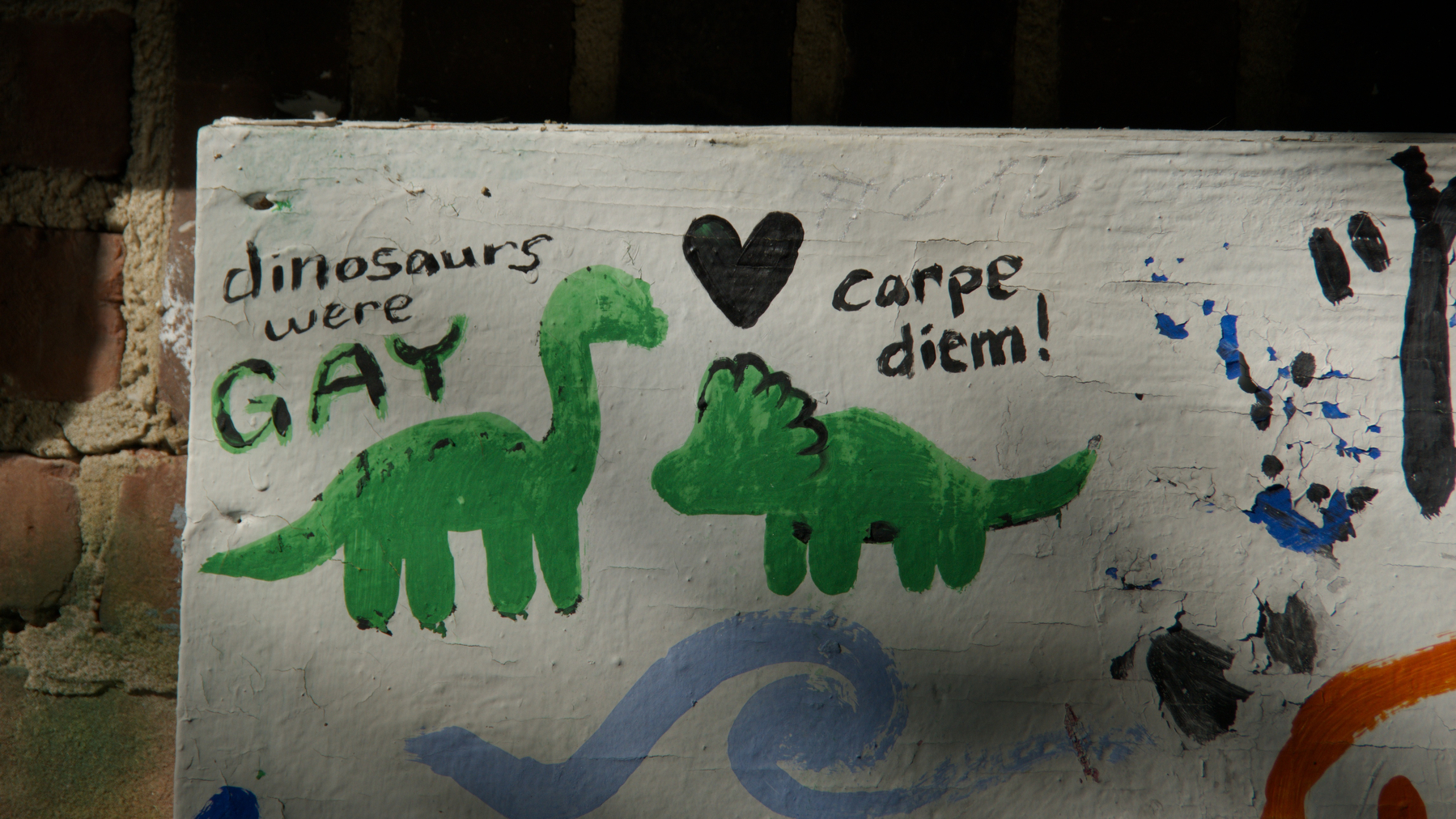 graffiti of two dinosaurs captioned "Dinosaurs were GAY" and "Carpe Diem"