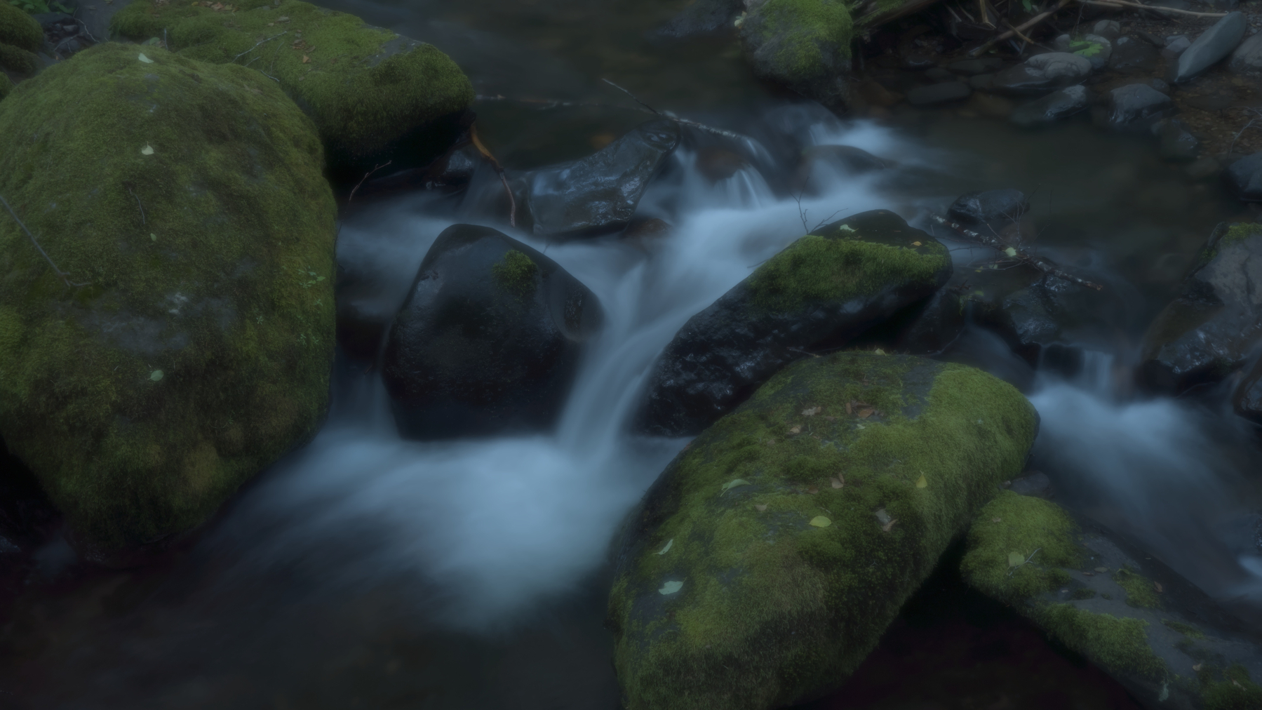 water flowing around mossy rocks&10;