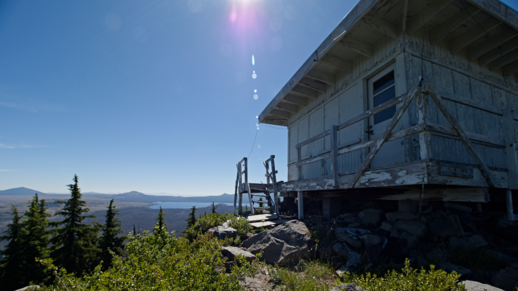 old fire lookout with forest, lake, and mountains beyond