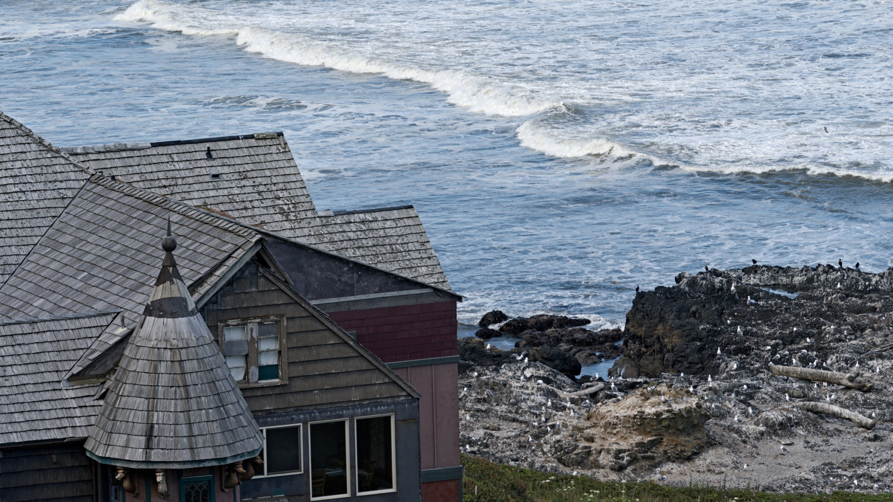 older house on rocky promontory above the waves