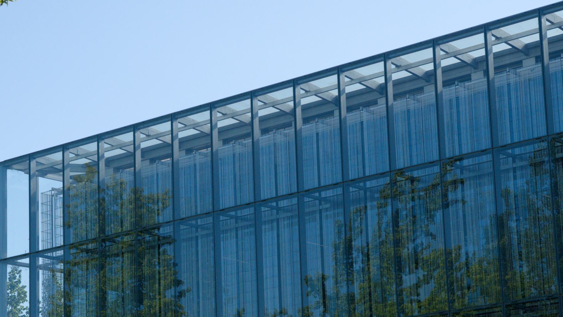 trees reflected by a glass-front building on the UO campus