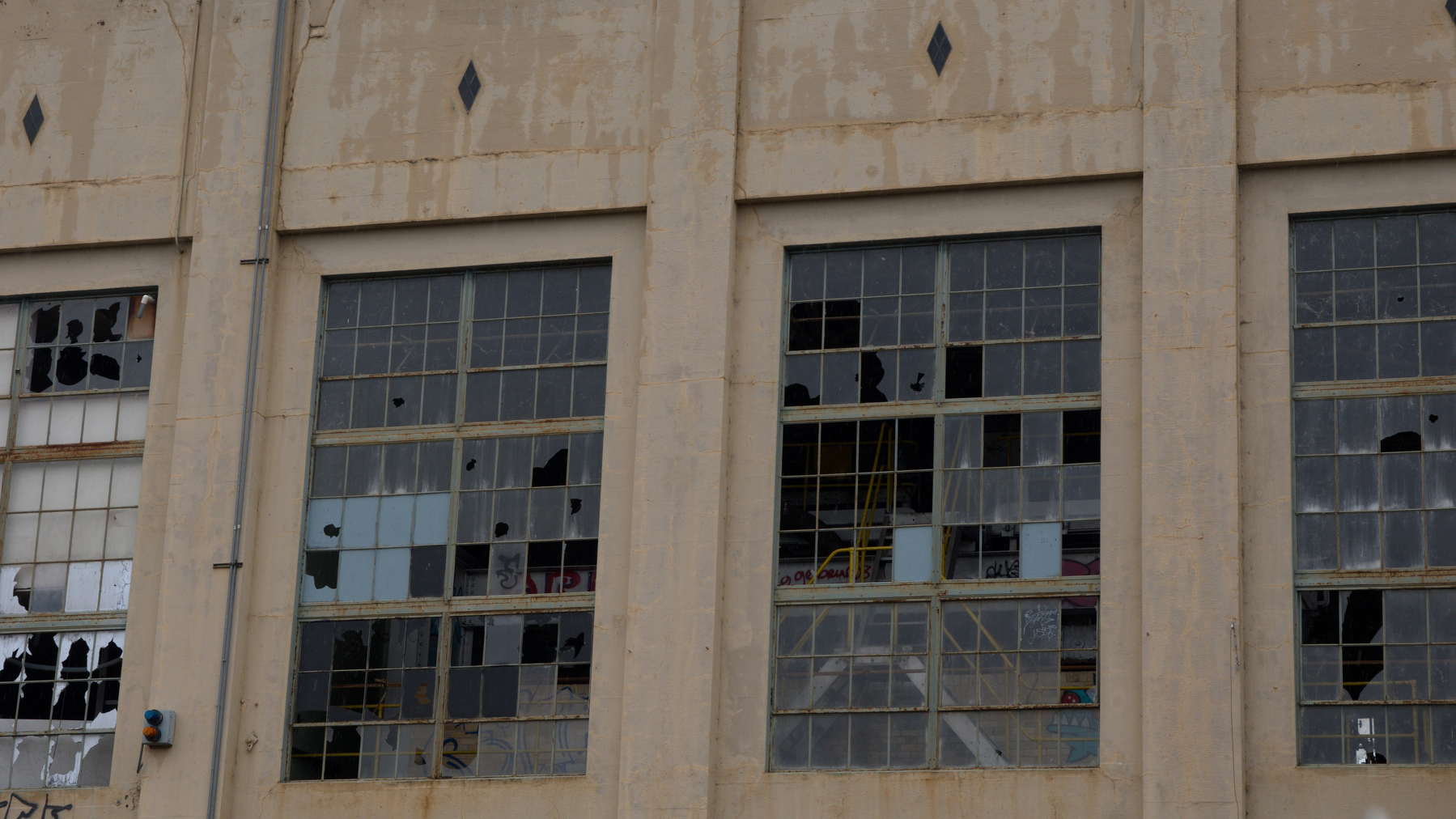 industrial building facade with broken windows and graffiti inside