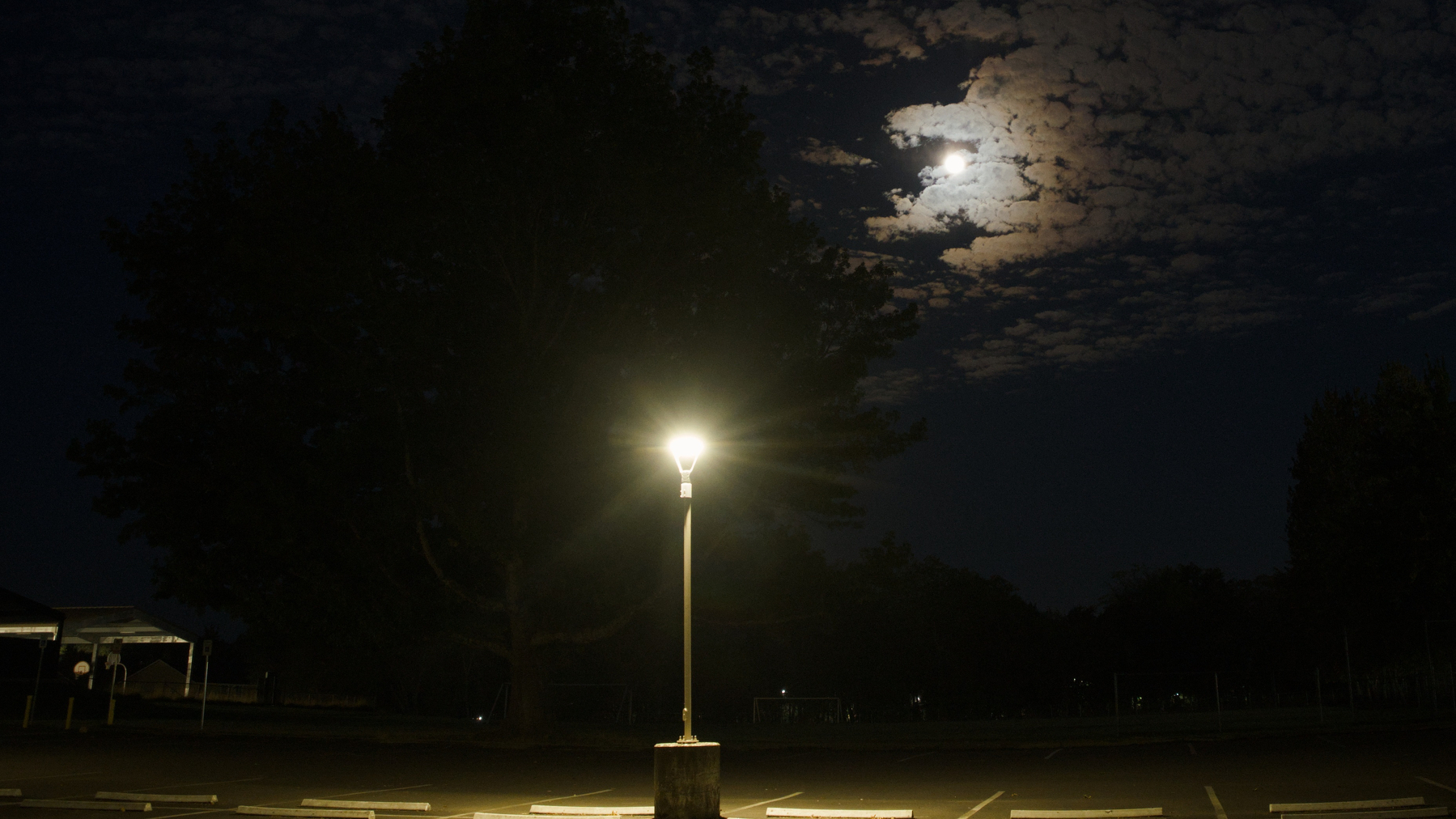 full moon lighting clouds with a street lamp in the foreground