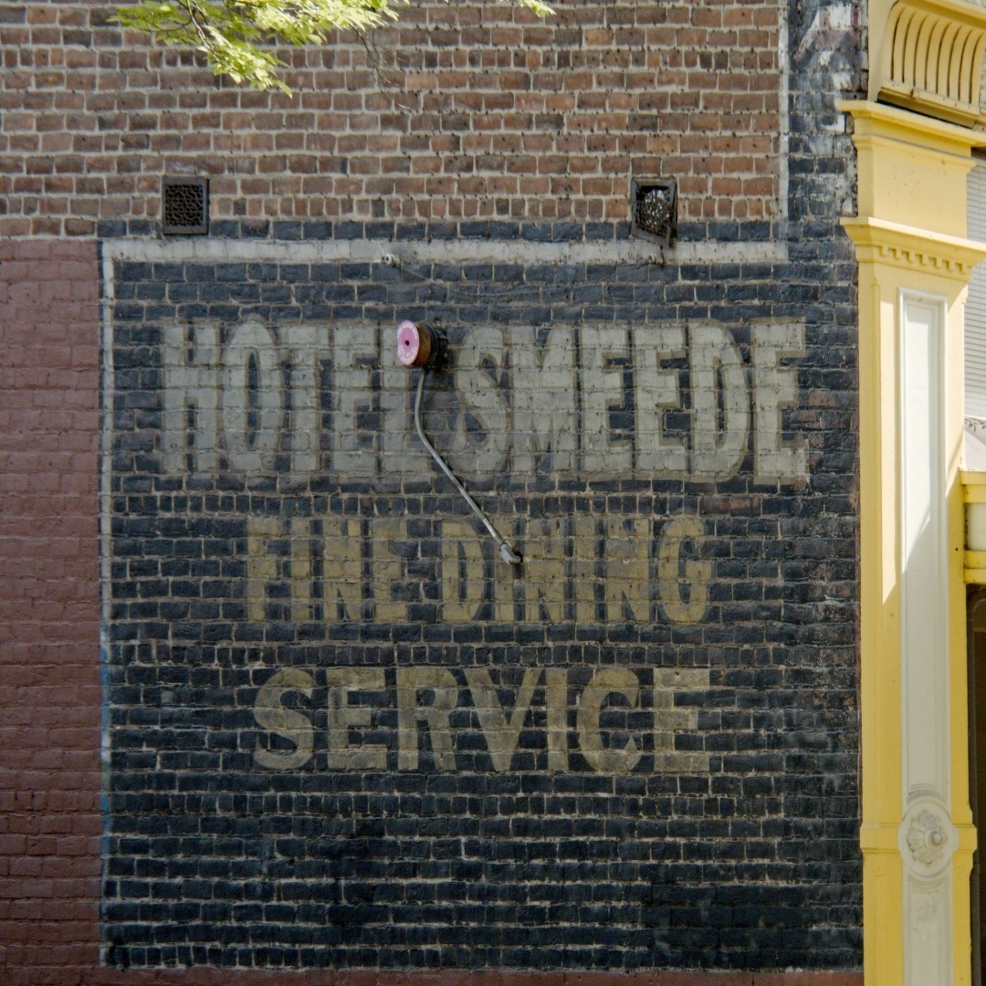 sign painted on a brick wall advertising HOTEL SMEEDE FINE DINING SERVICE