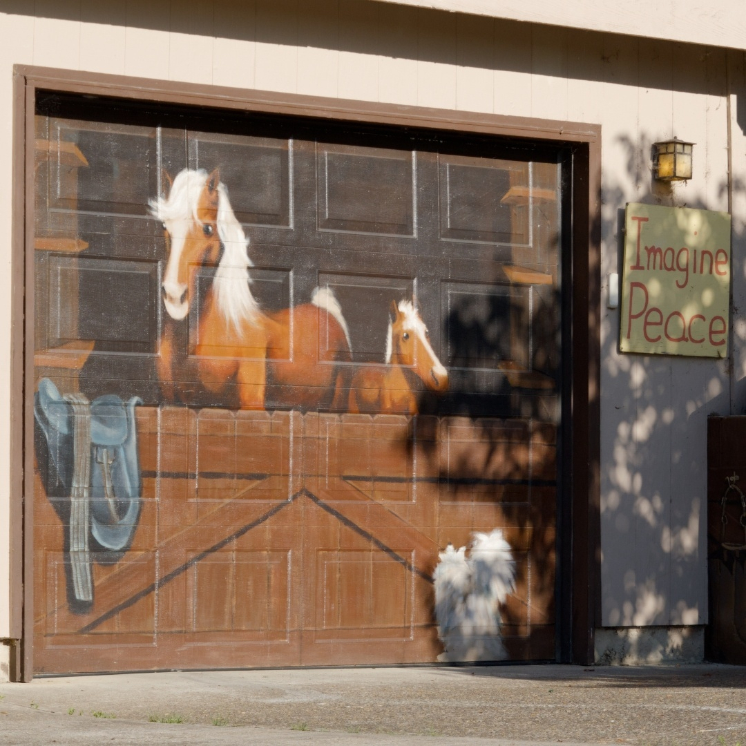 a garage door painted with a horse in a stable scene and a sign saying Imagine Peace
