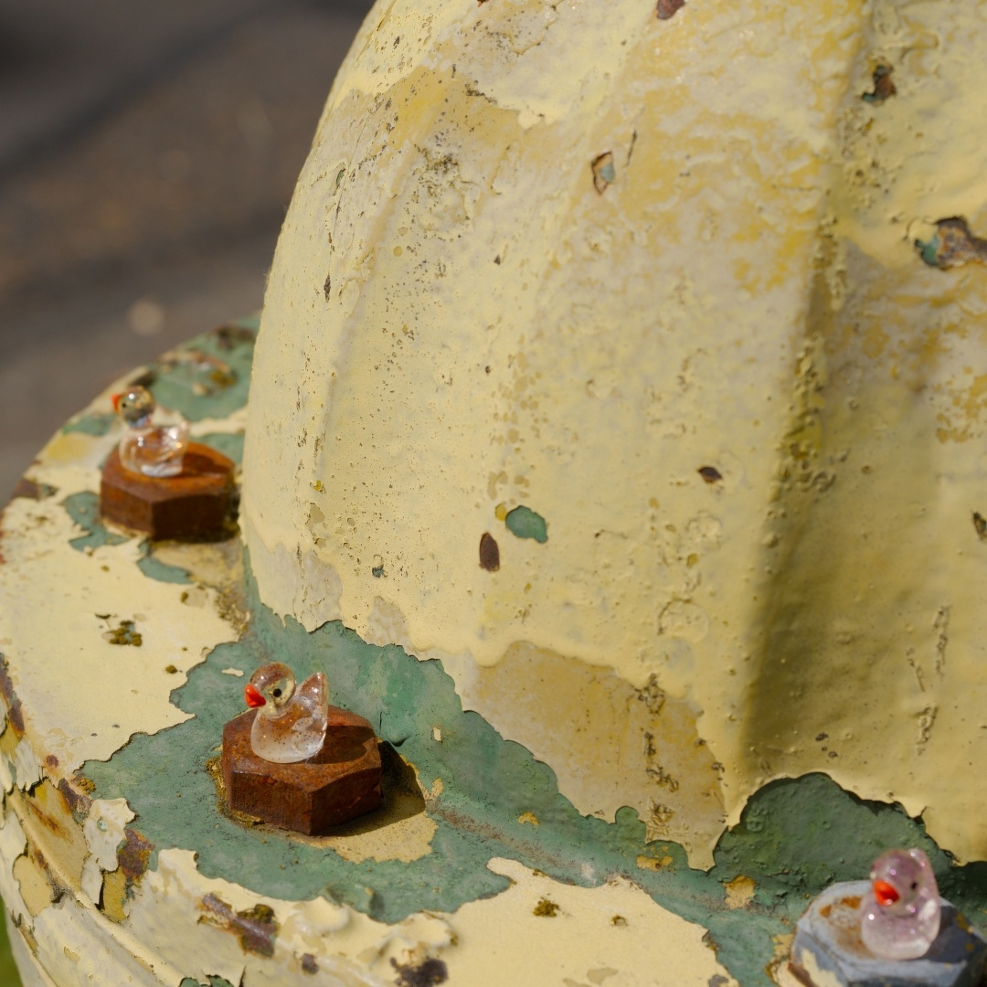 Fire hydrant with tiny plastic ducks glued on the bolt heads.