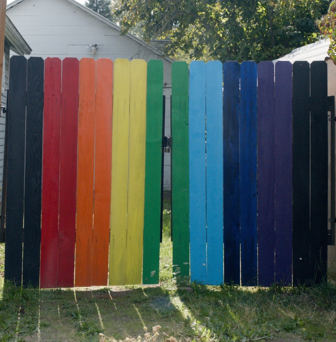 Wooden fence painted all the colors of the rainbow