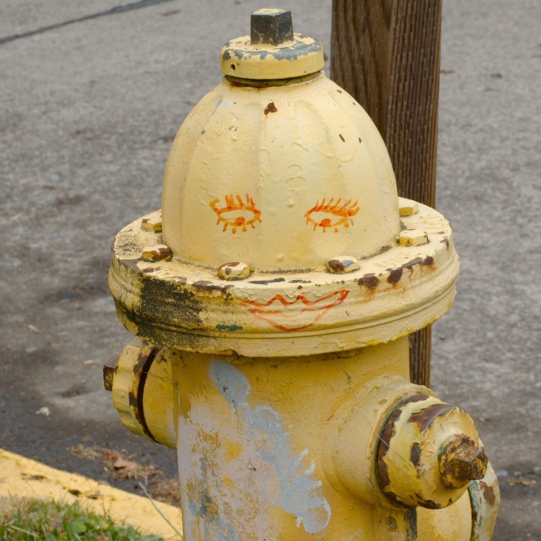 yellow fire hydrant with eyes and a smiling mouth drawn on