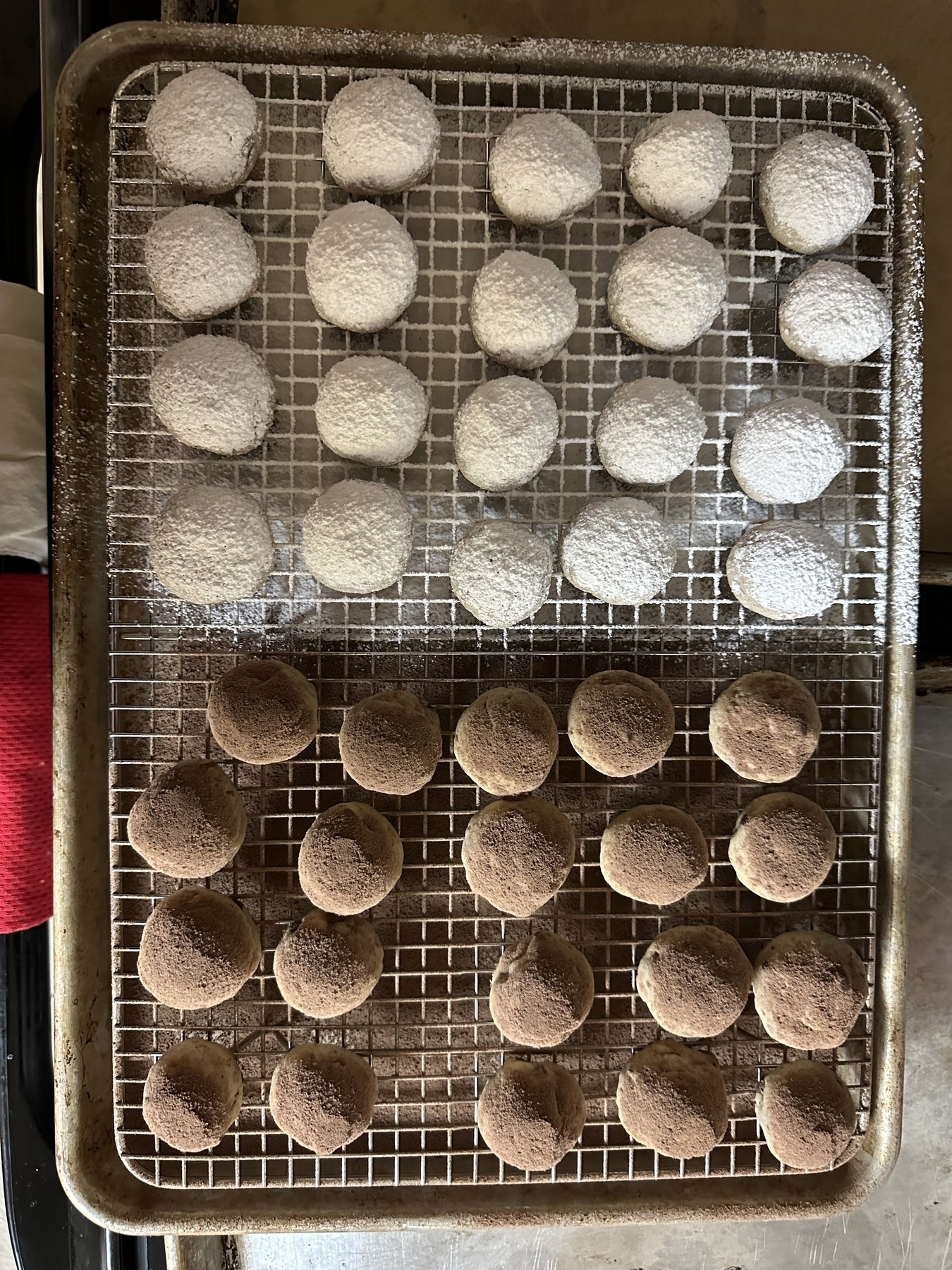Tray full of round cookies, half covered in powdered sugar and half in chocolate powder.