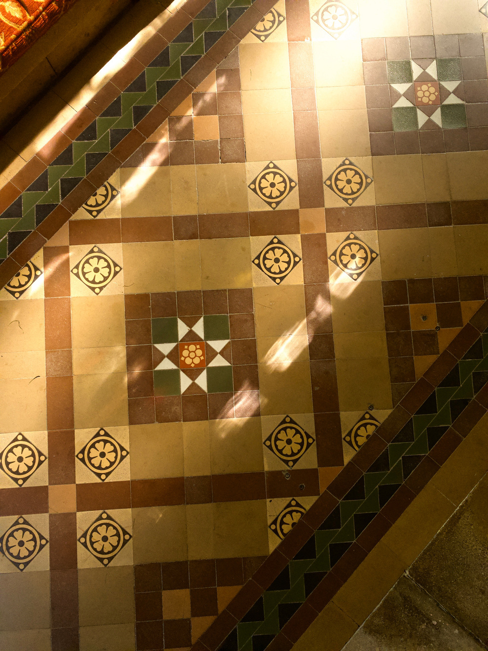 A decorative mosaic floor features a geometric pattern with floral motifs and a mix of brown, green, and beige tiles.