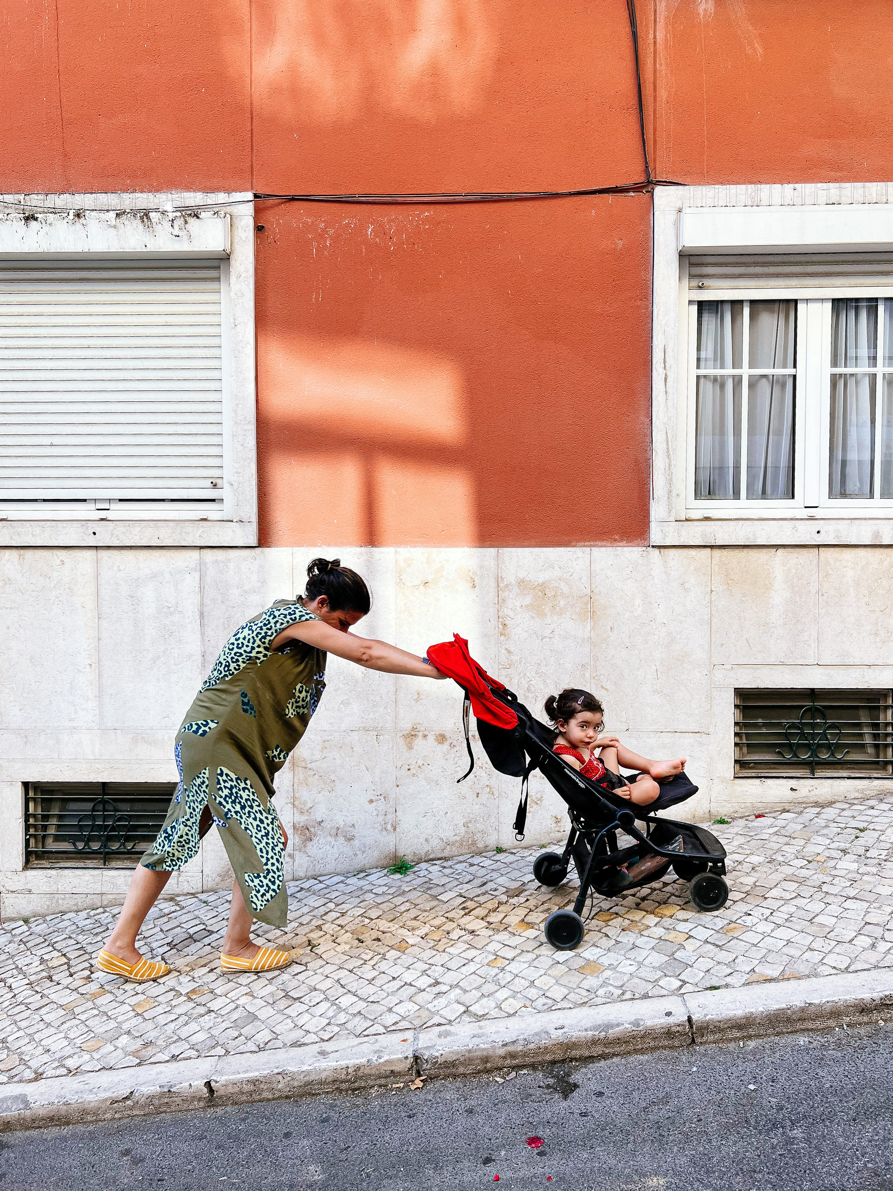 A mom pushes a stroller up a steep street