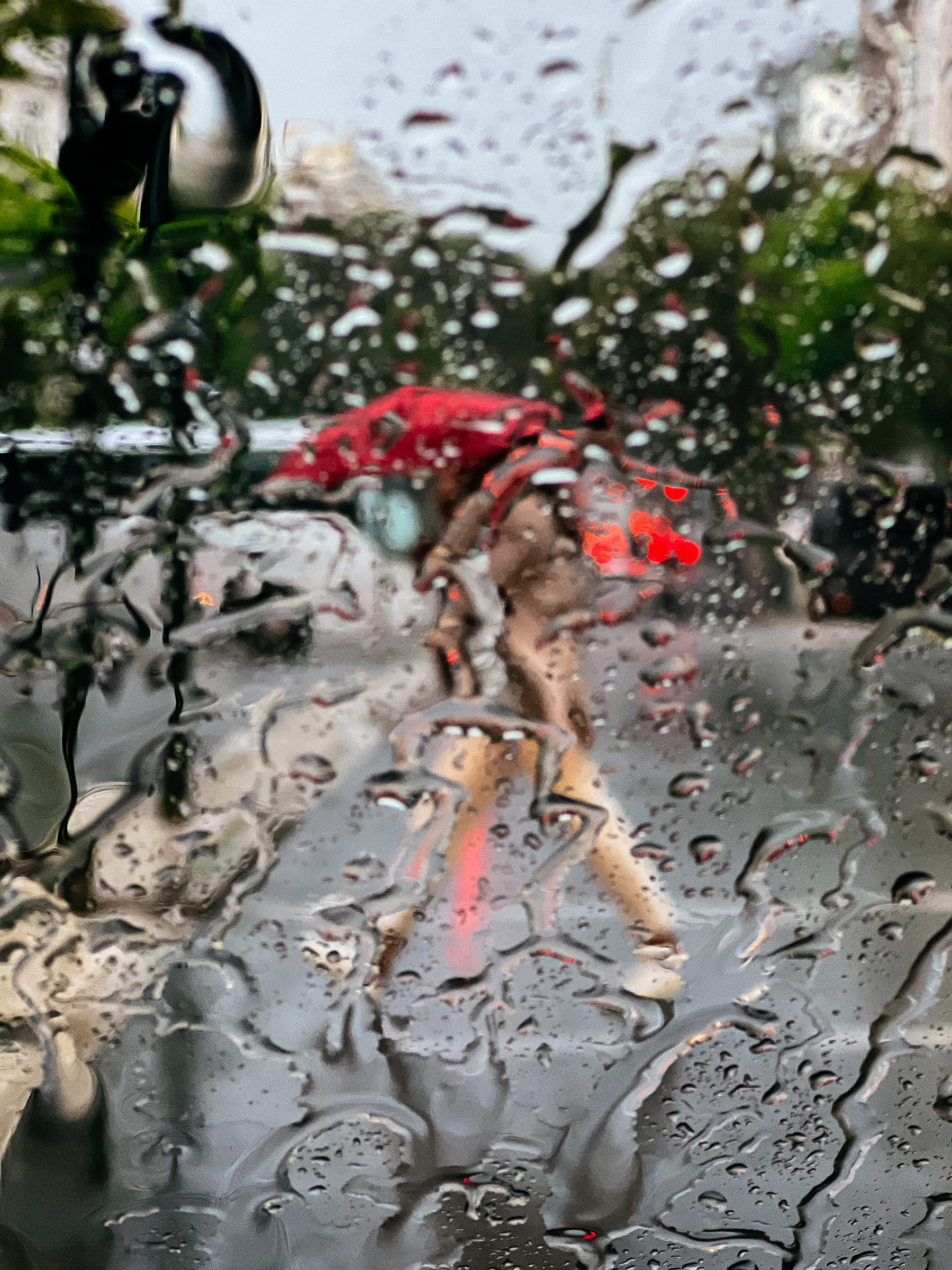 rain drops on a windshield with someone out of focus on the background