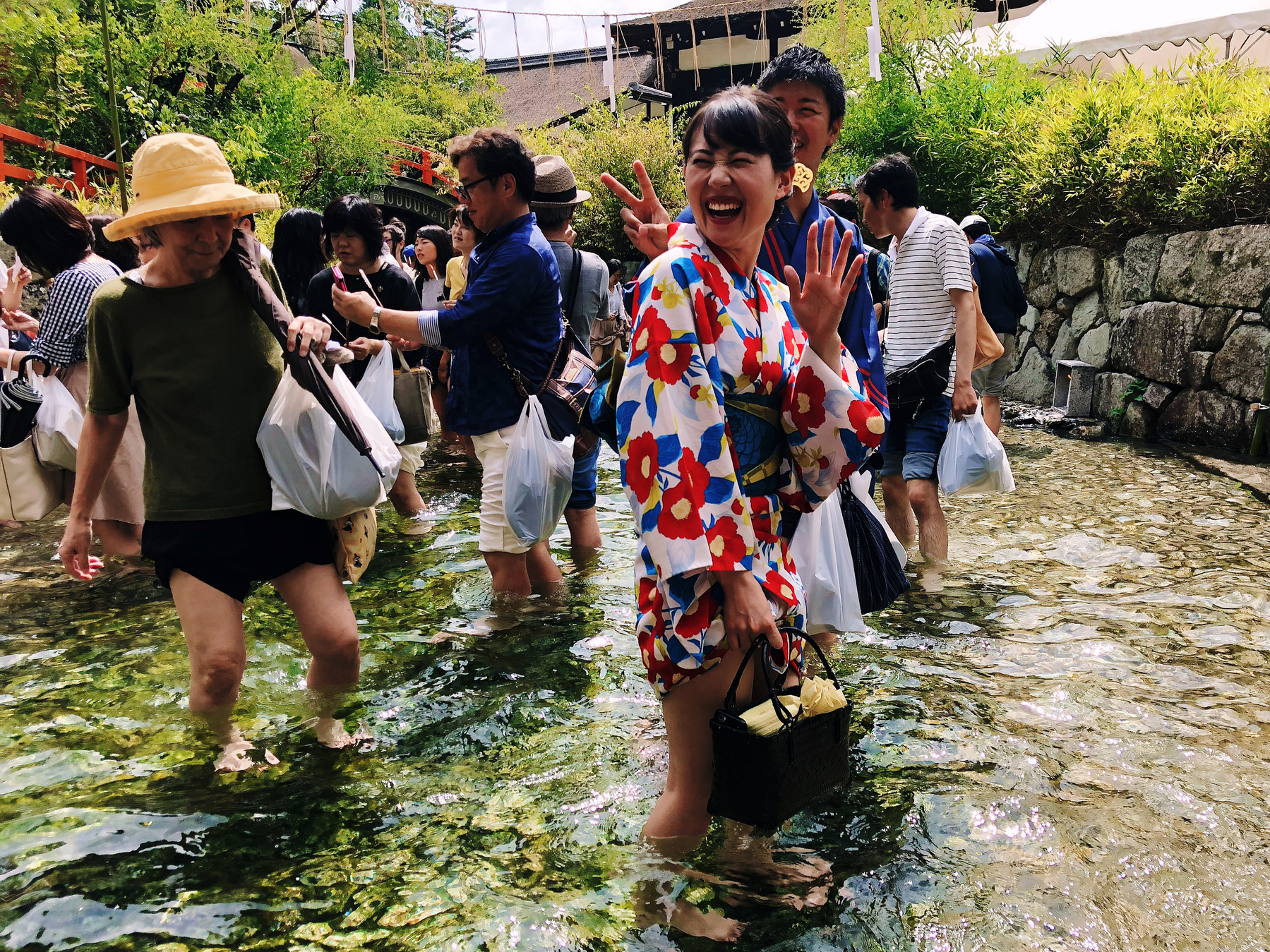 Festival goers on a temple, walking in a cold stream of water, happy.