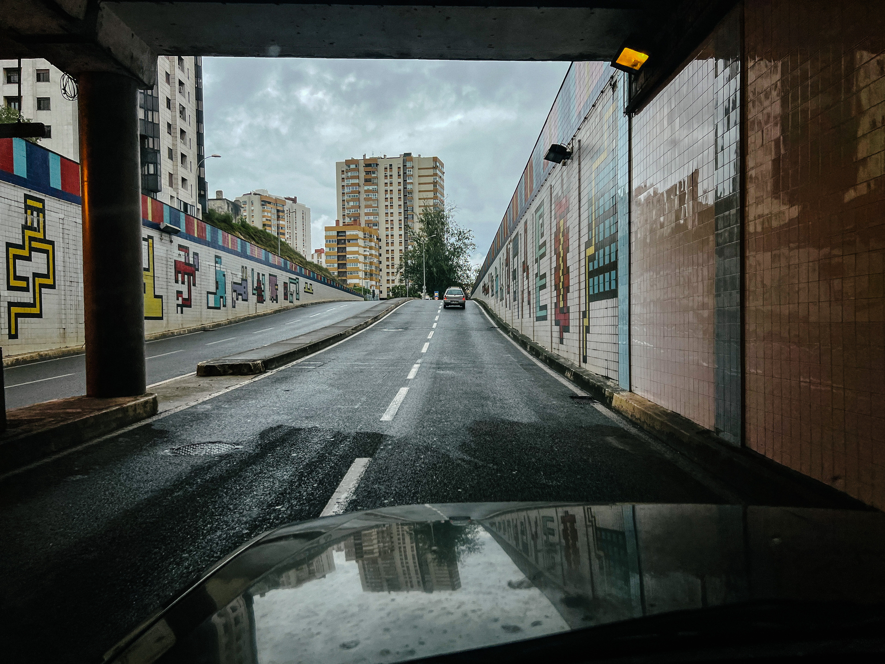 From the drivers seat, exiting a tunnel. A building up ahead, street art on the tunnel’s walls