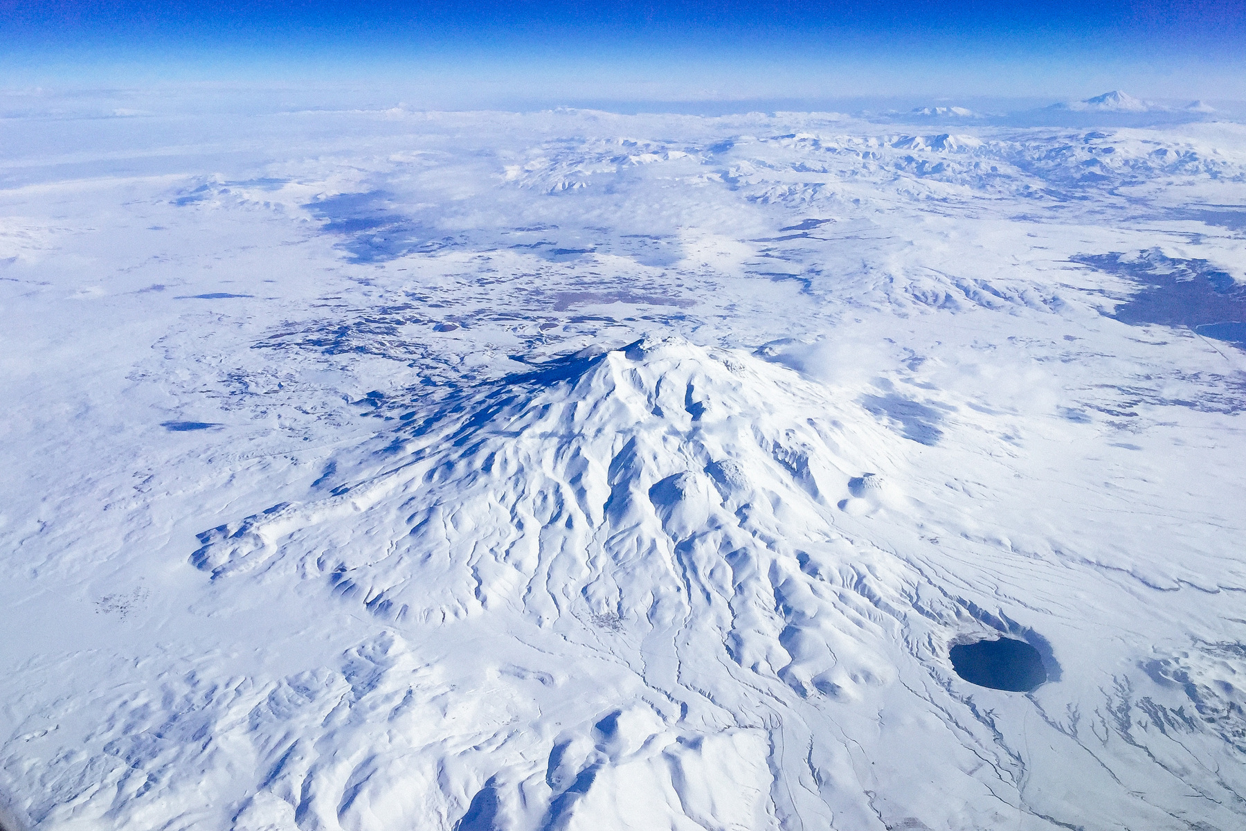 Another photo taken from an airplane, this one shows snow covered landscape, with some mountains.