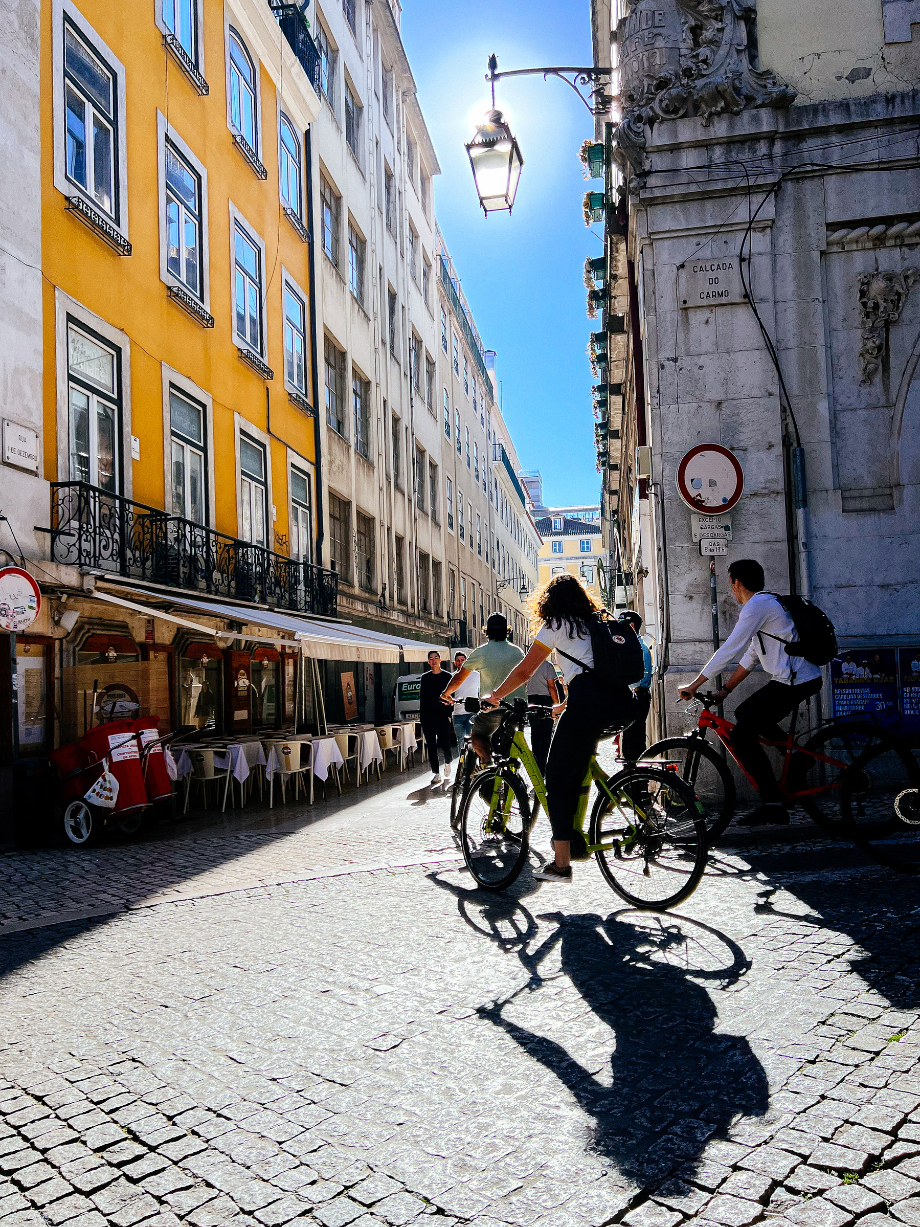 Cyclists turn a corner in the old part of town. Backlit. 