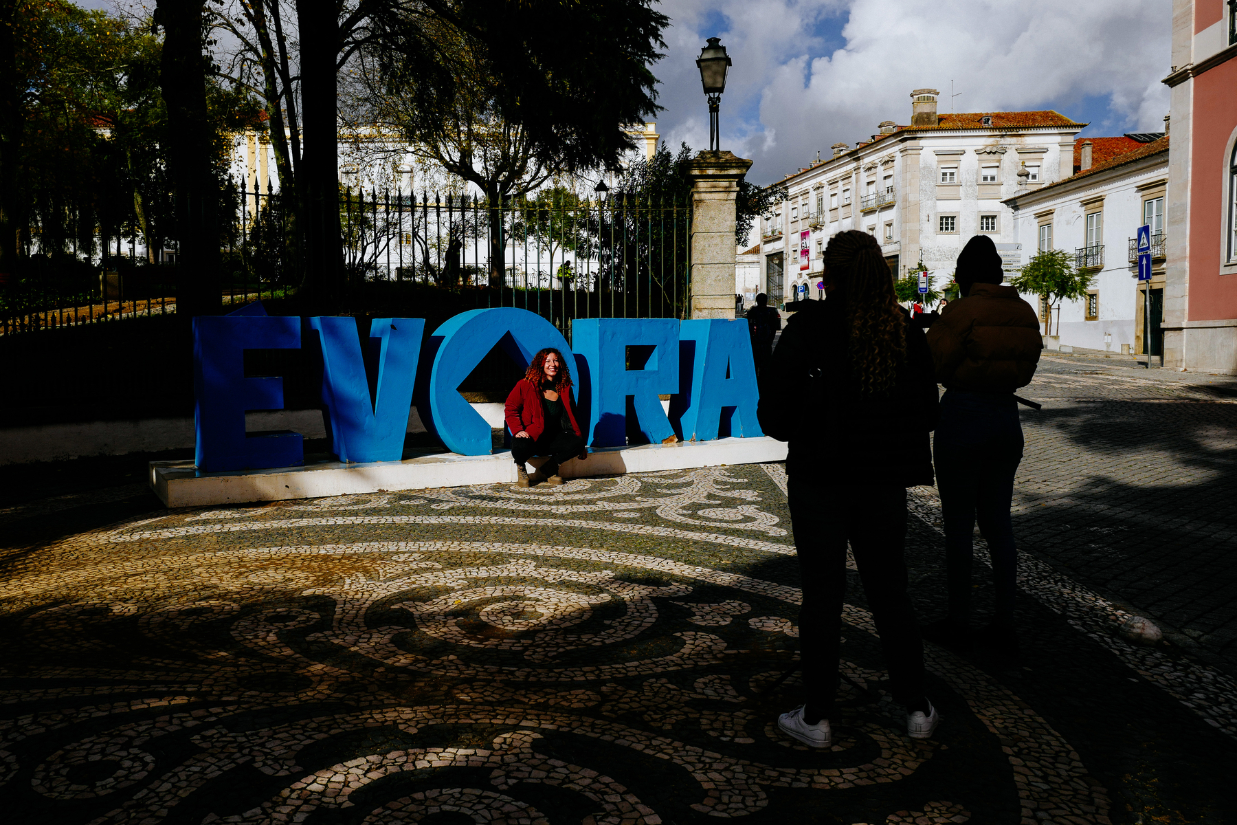 People take photos in front of an “Evora” sign. 