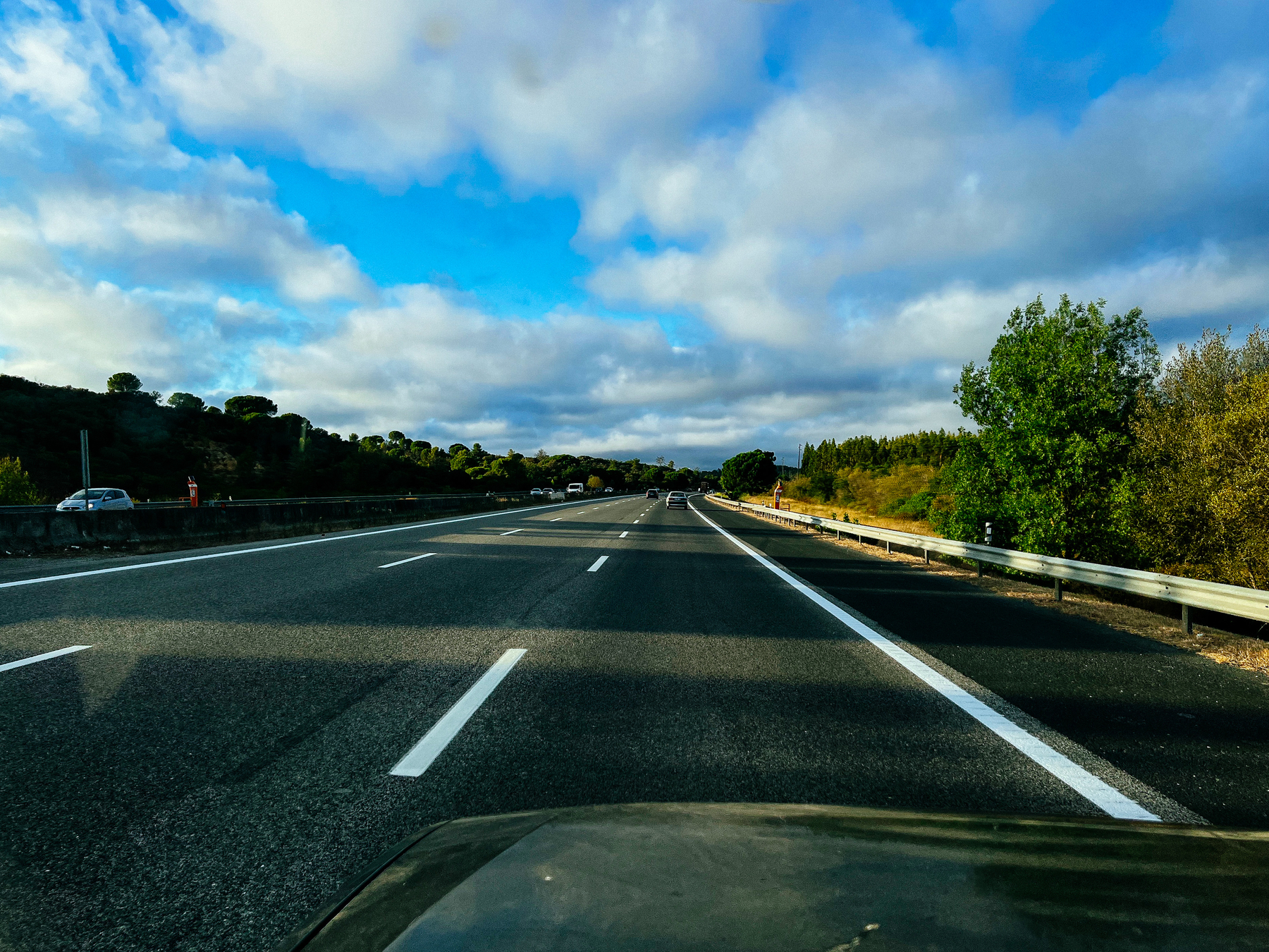 a mostly empty highway, with a cloudy sky above