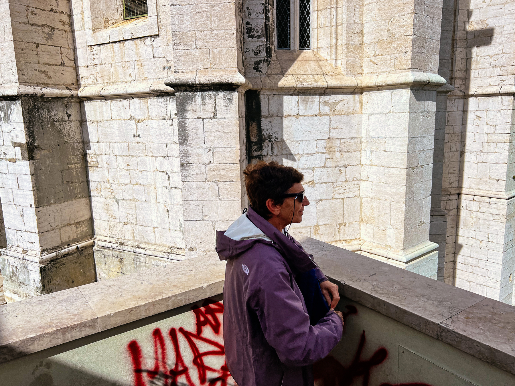 a woman looks at something outside the frame, church wall on the background
