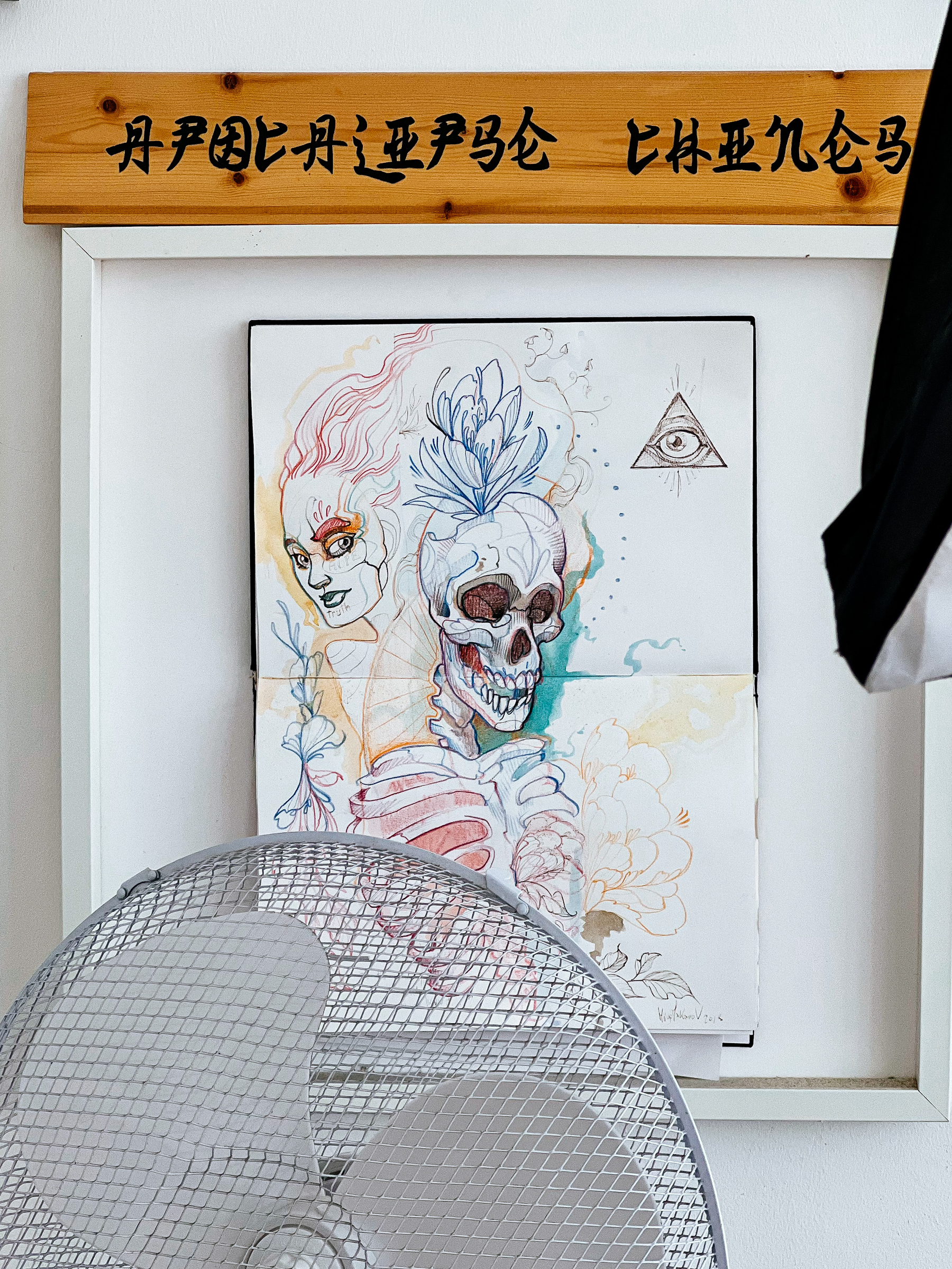Framed illustration, a skull and a woman’s face. 