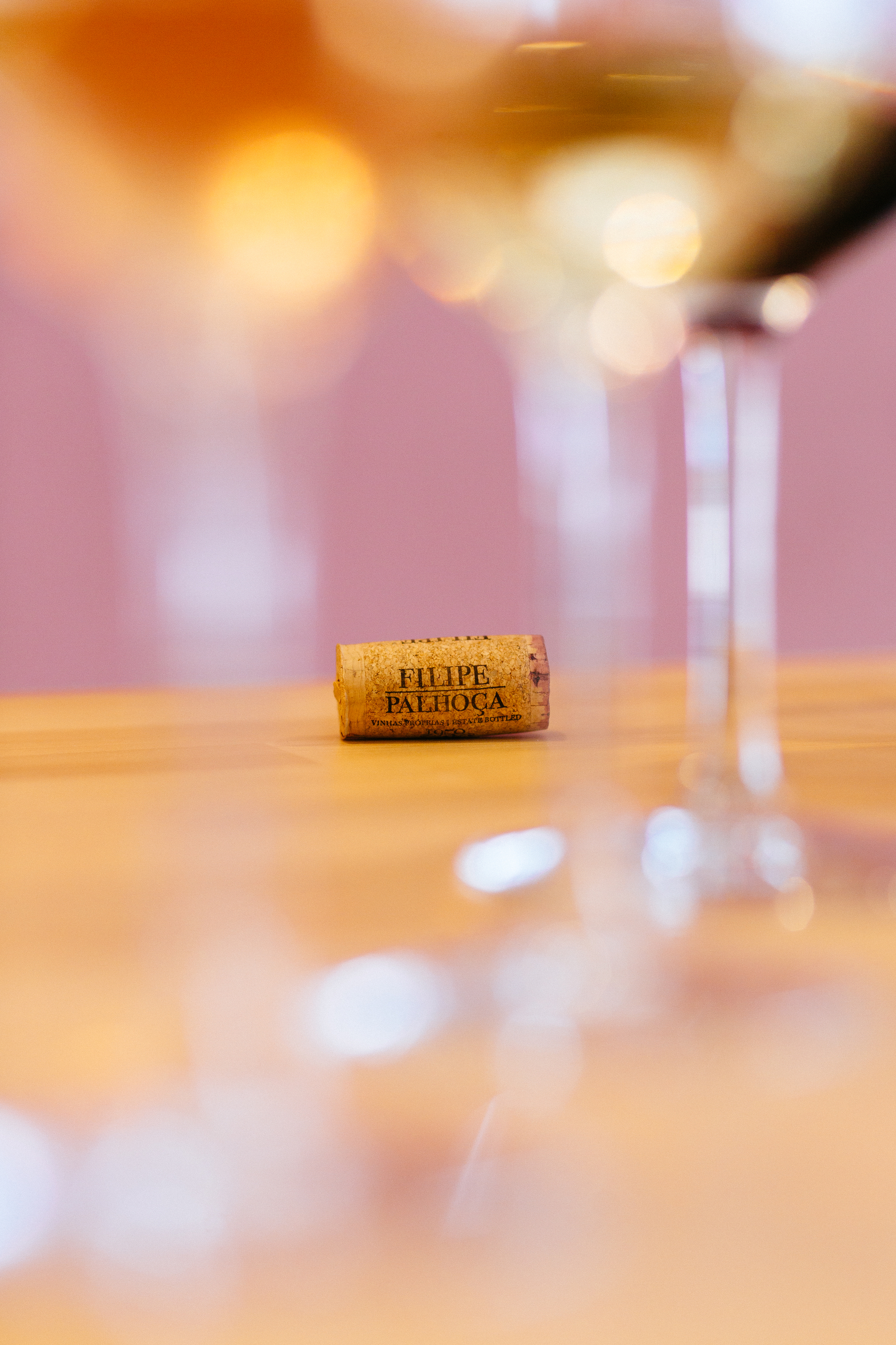 A wine cork sits among out of focus glasses of wine