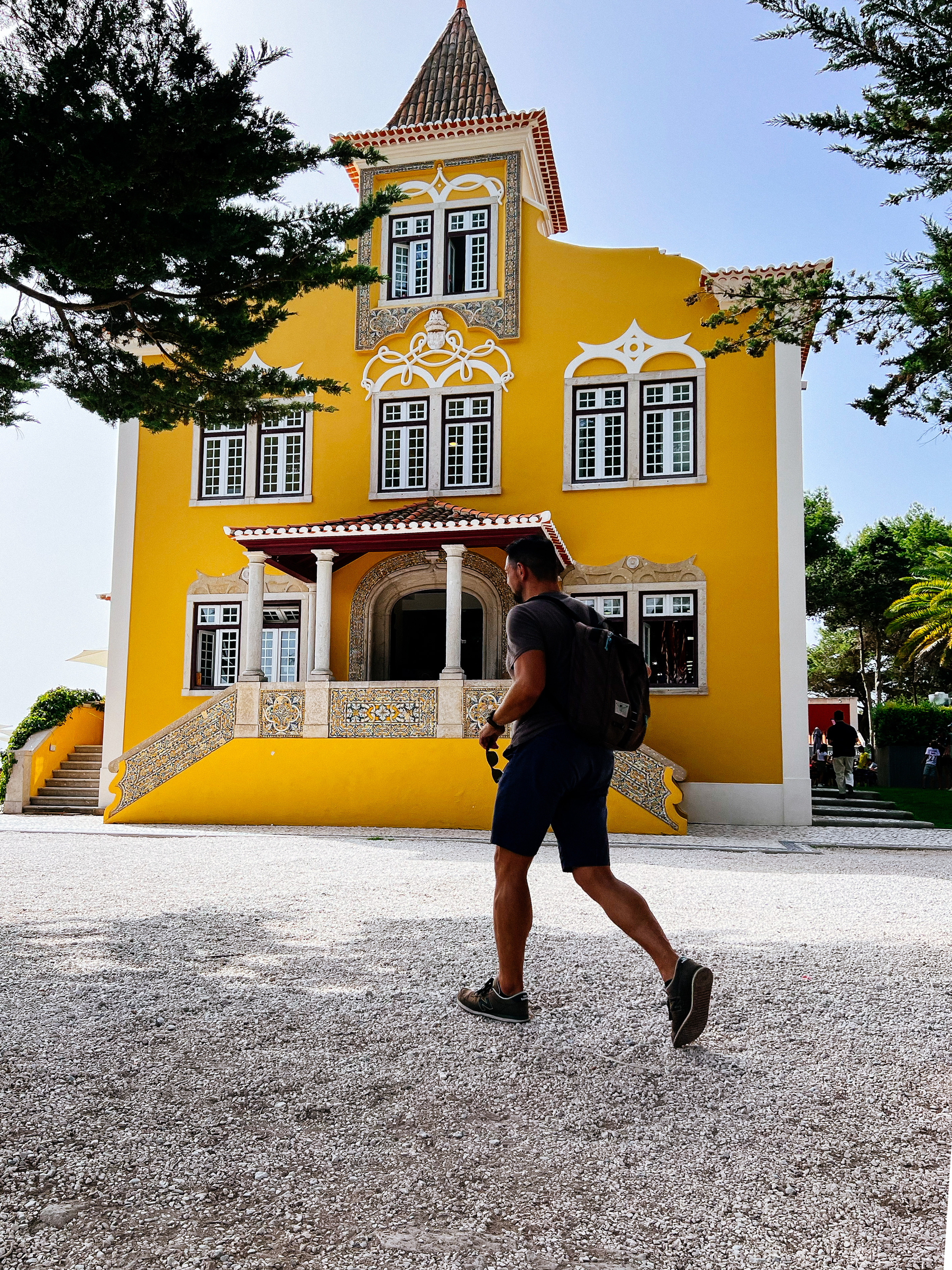 A man walks in front of a cool looking yellow building, palatial 