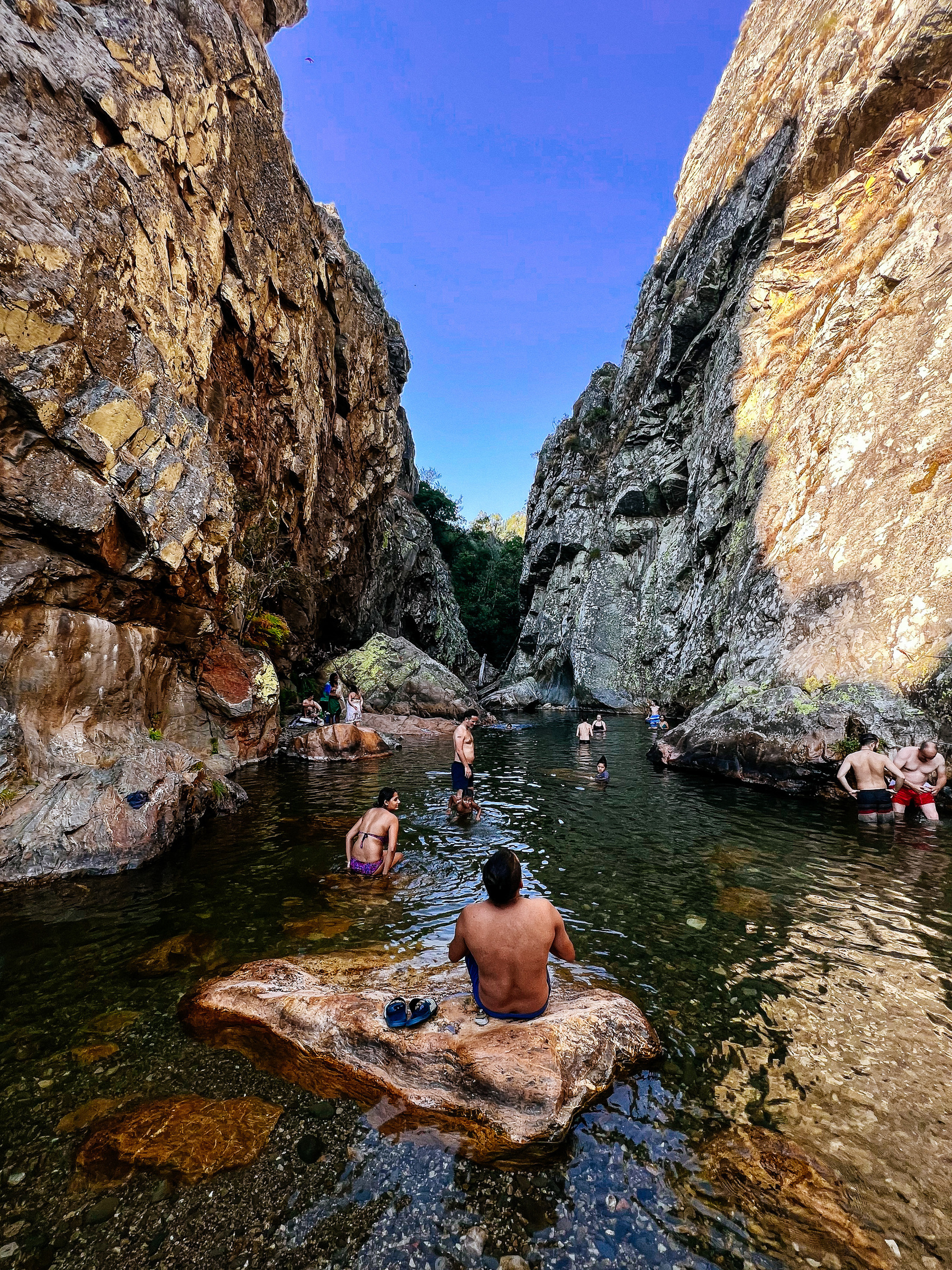 A mini pool, on a small canyon. People enjoying the cool water. 