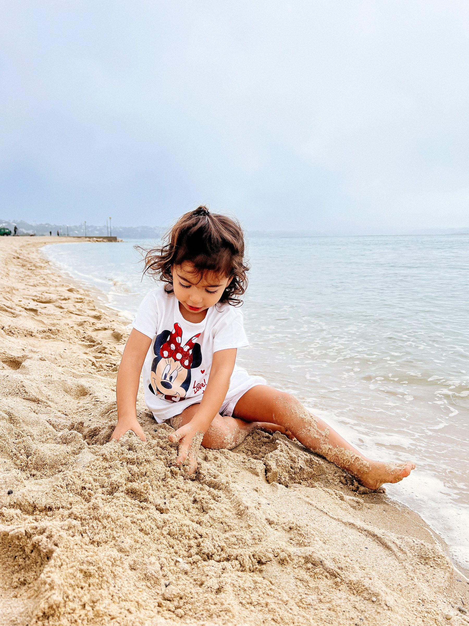 Toddler by the sea, playing in the sand