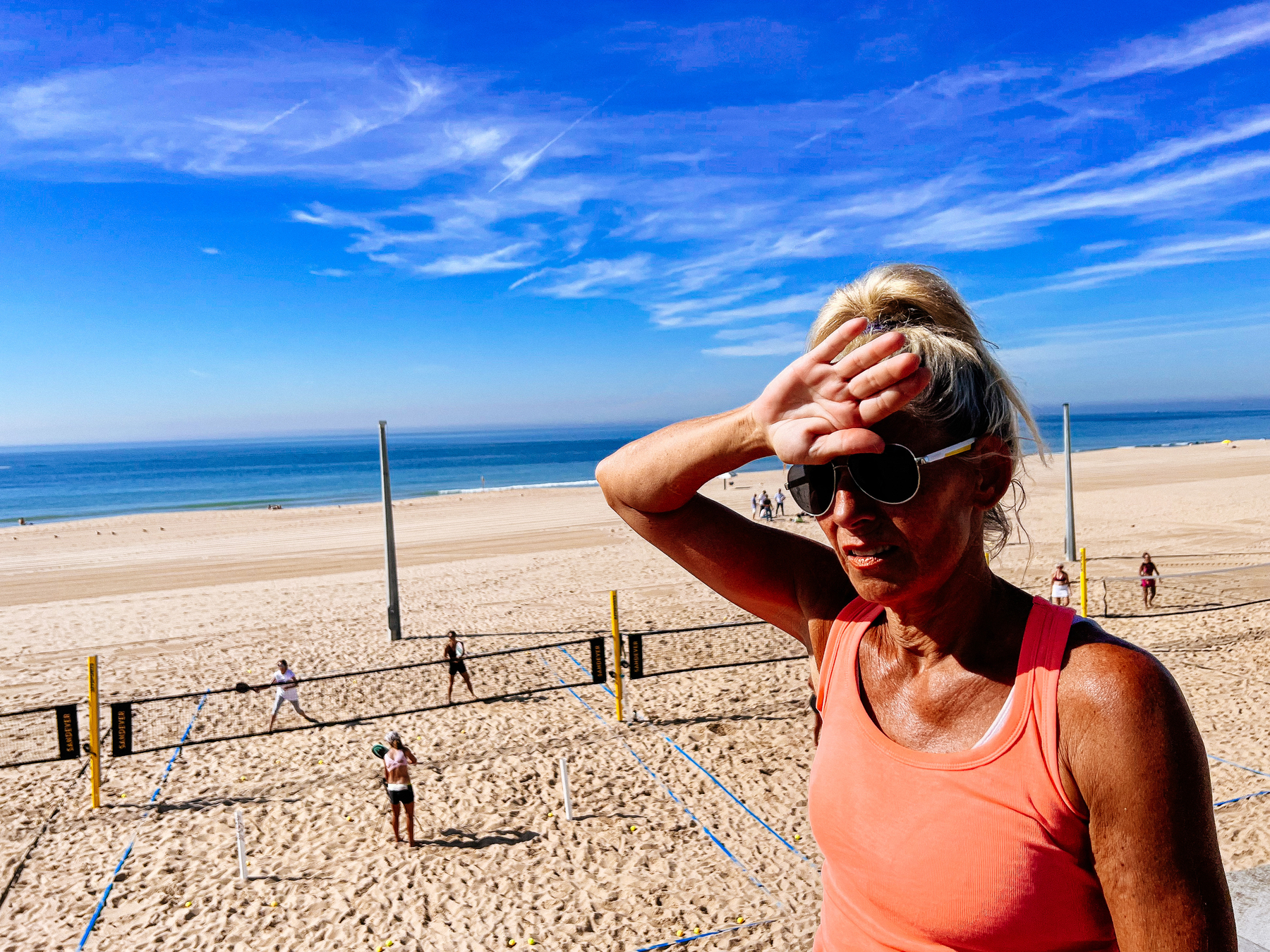 A woman shields her eyes at the beach