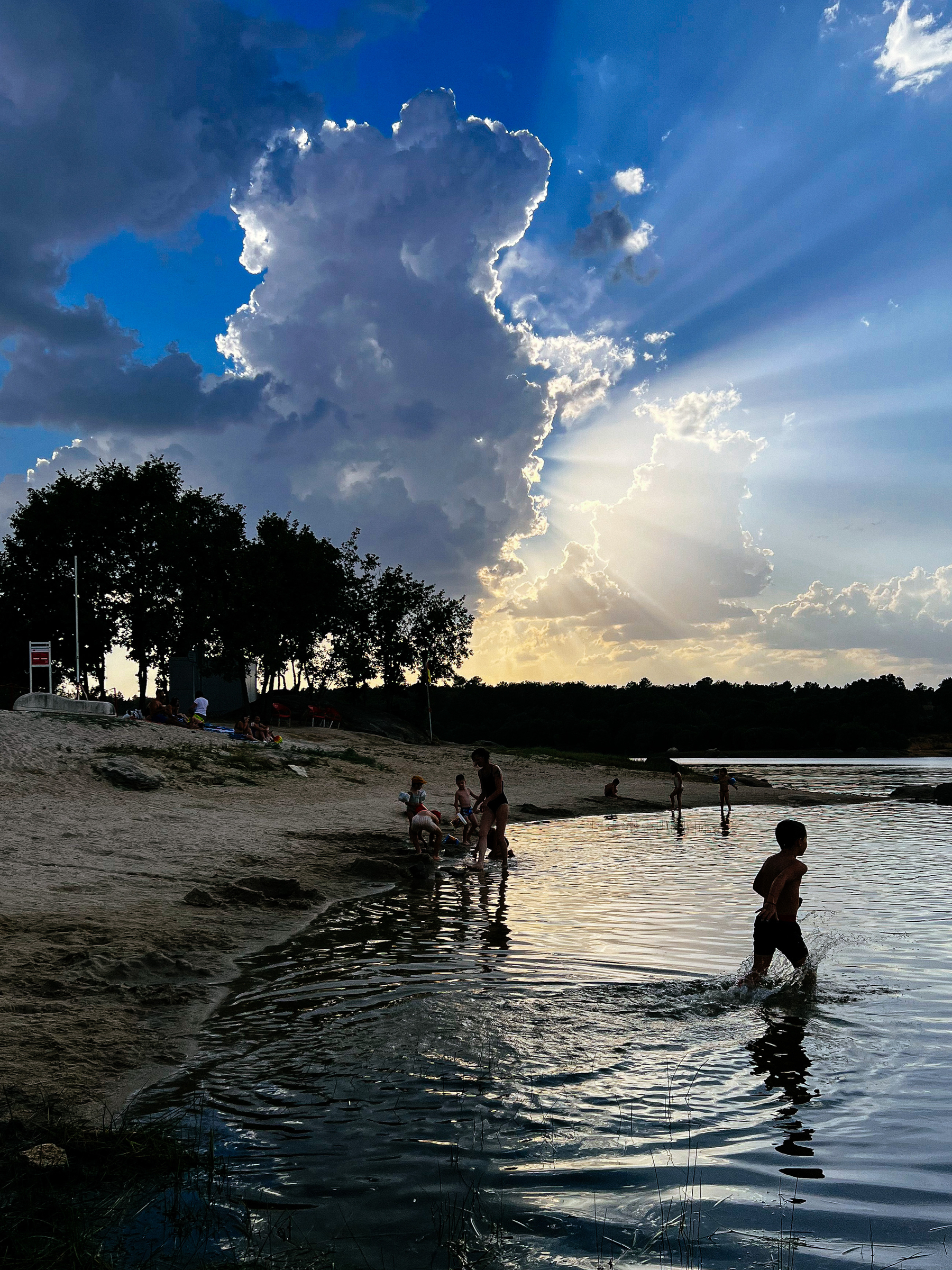 a boy has fun in the lake, with a huge cloud behind him