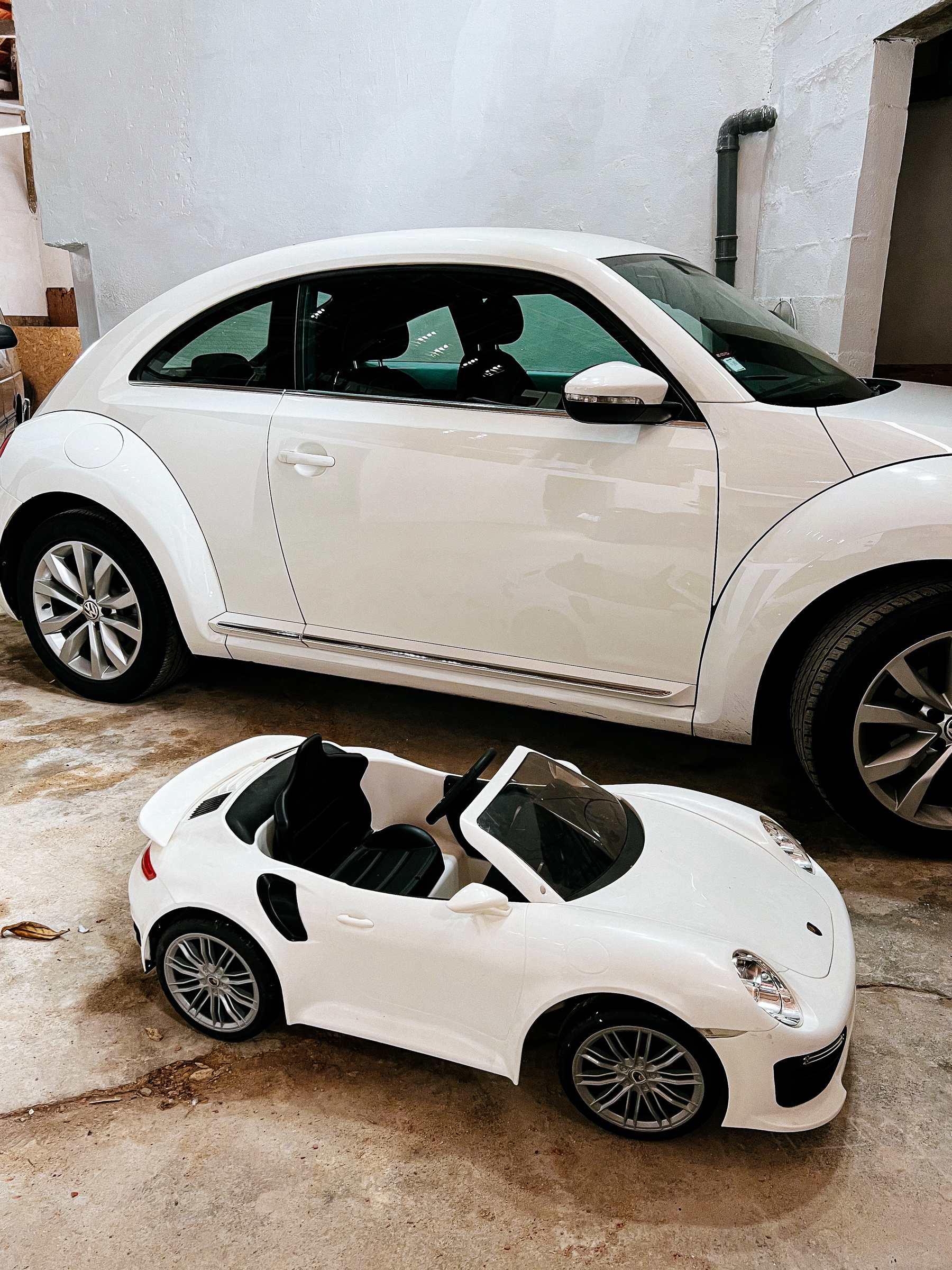 Two white cars. One regular sized, and a much smaller one, fit for a toddler. 