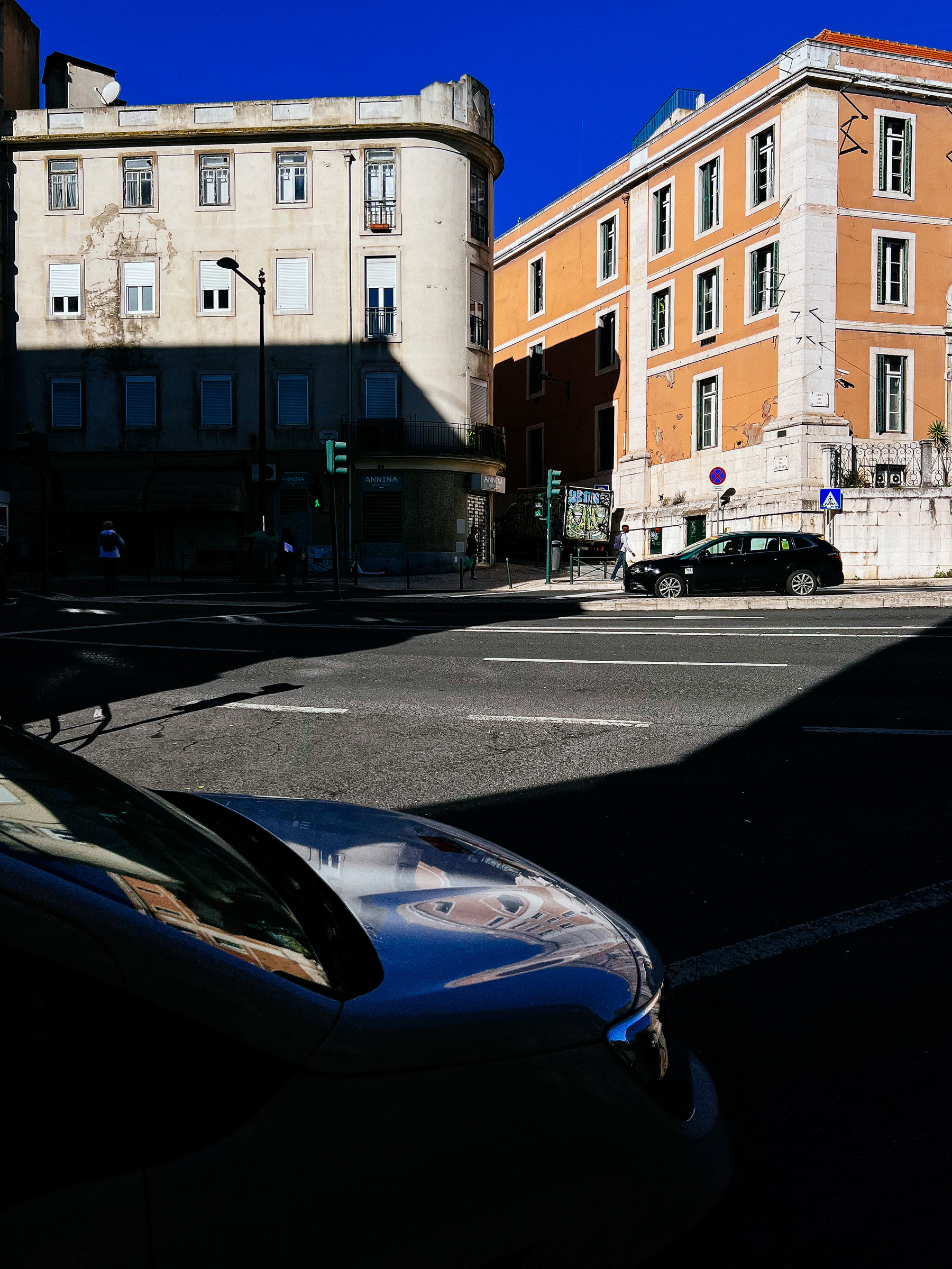 A street corner with deep shadows, and some cars 
