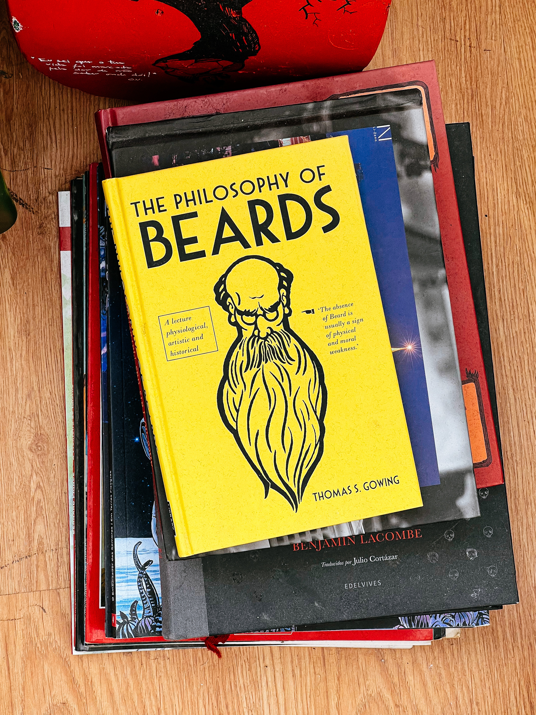 Looking down on a pile of books, with the cover of “The Philosophy of Beards” on top. 
