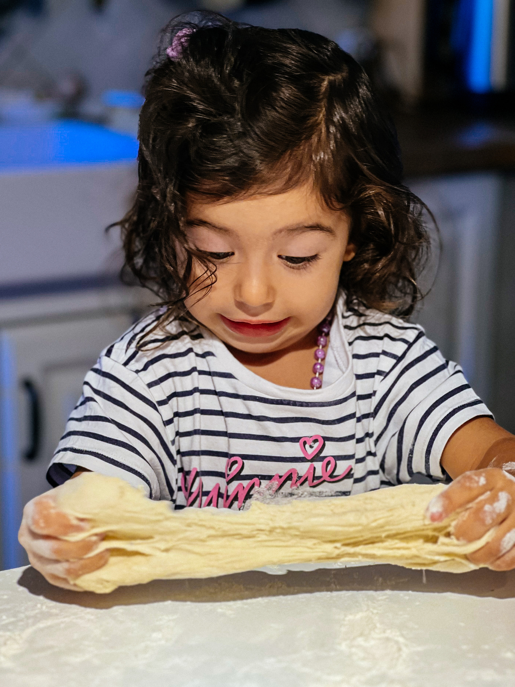 toddler stretches pizza dough