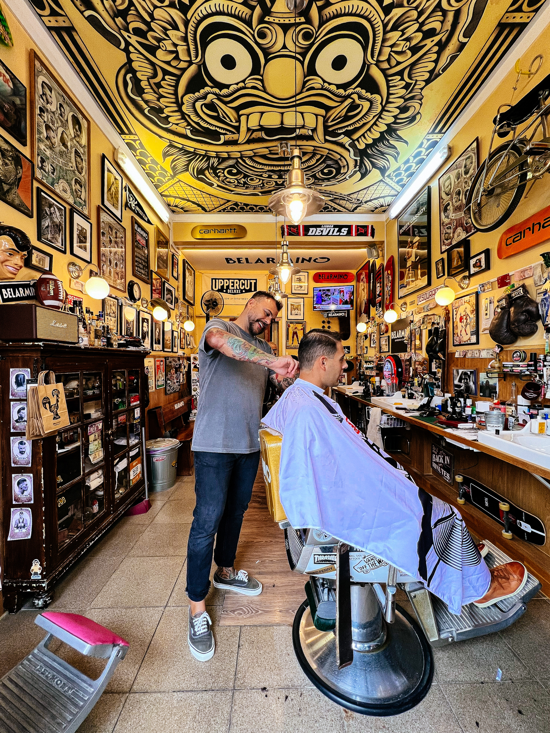 A barbershop with a Balinese design on the ceiling, a patron is getting a haircut