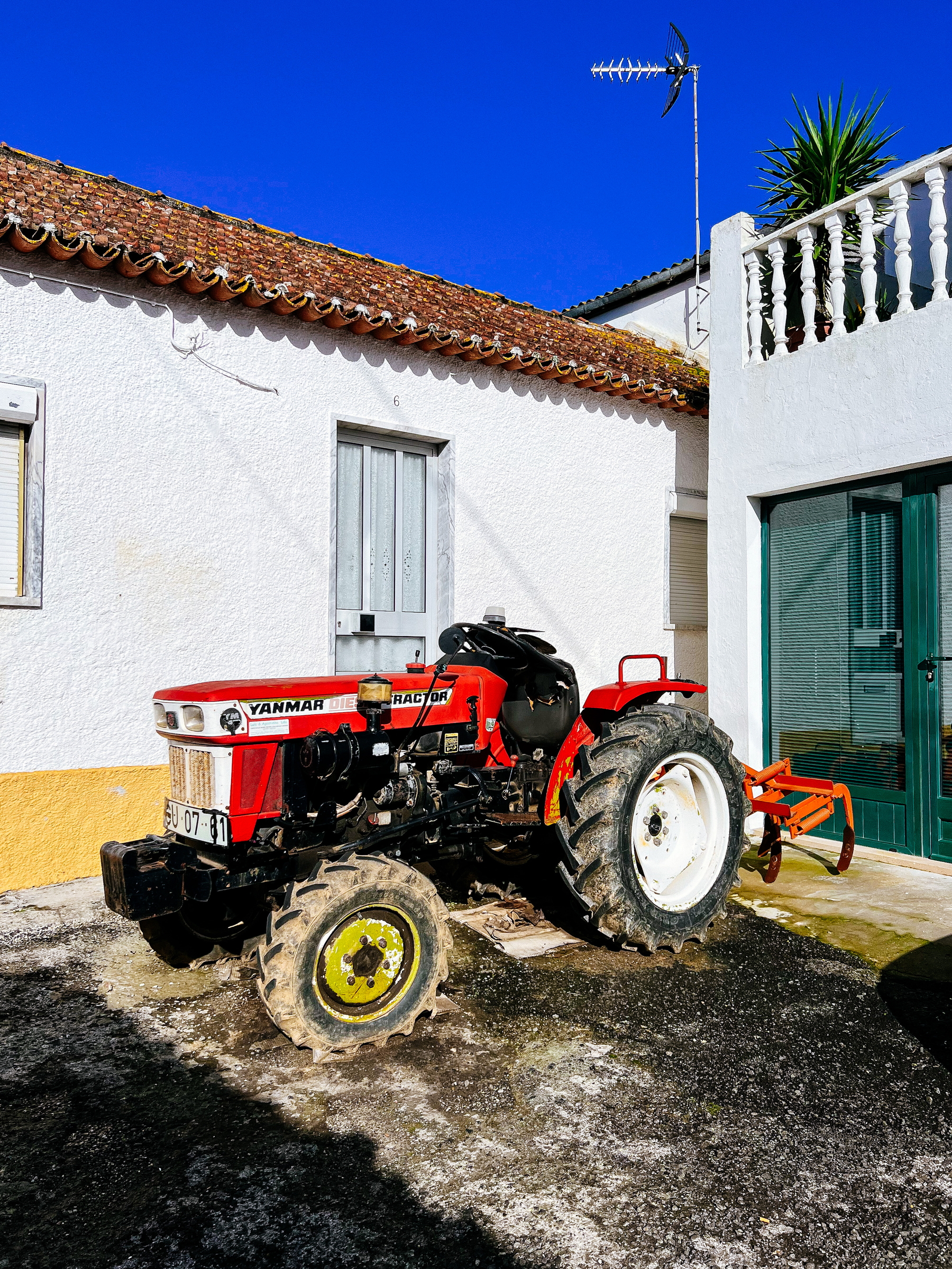 A tractor is parked outside a farmer’s house. 