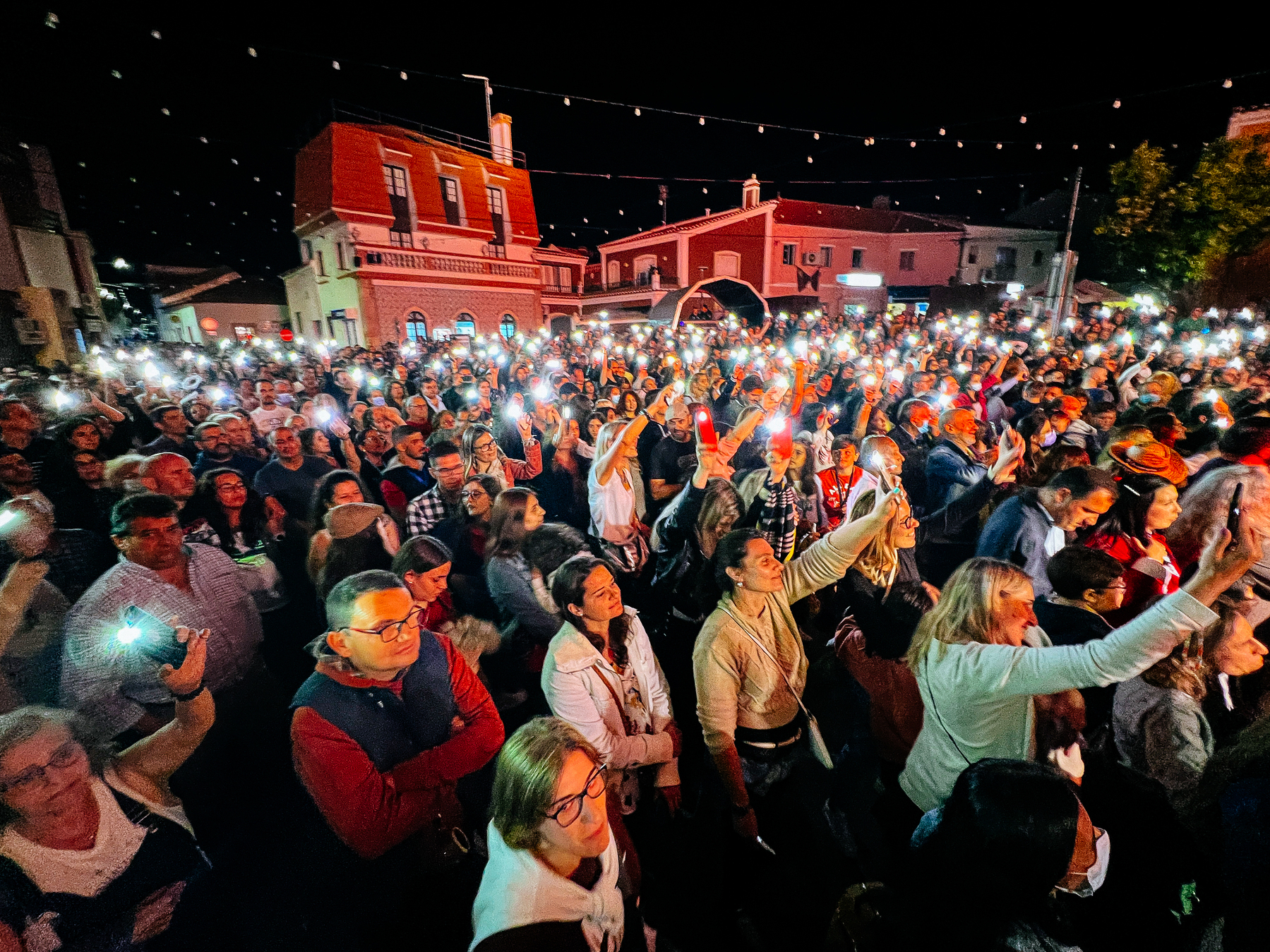 A crowd hold up their phones with the lantern turned on during a concert.