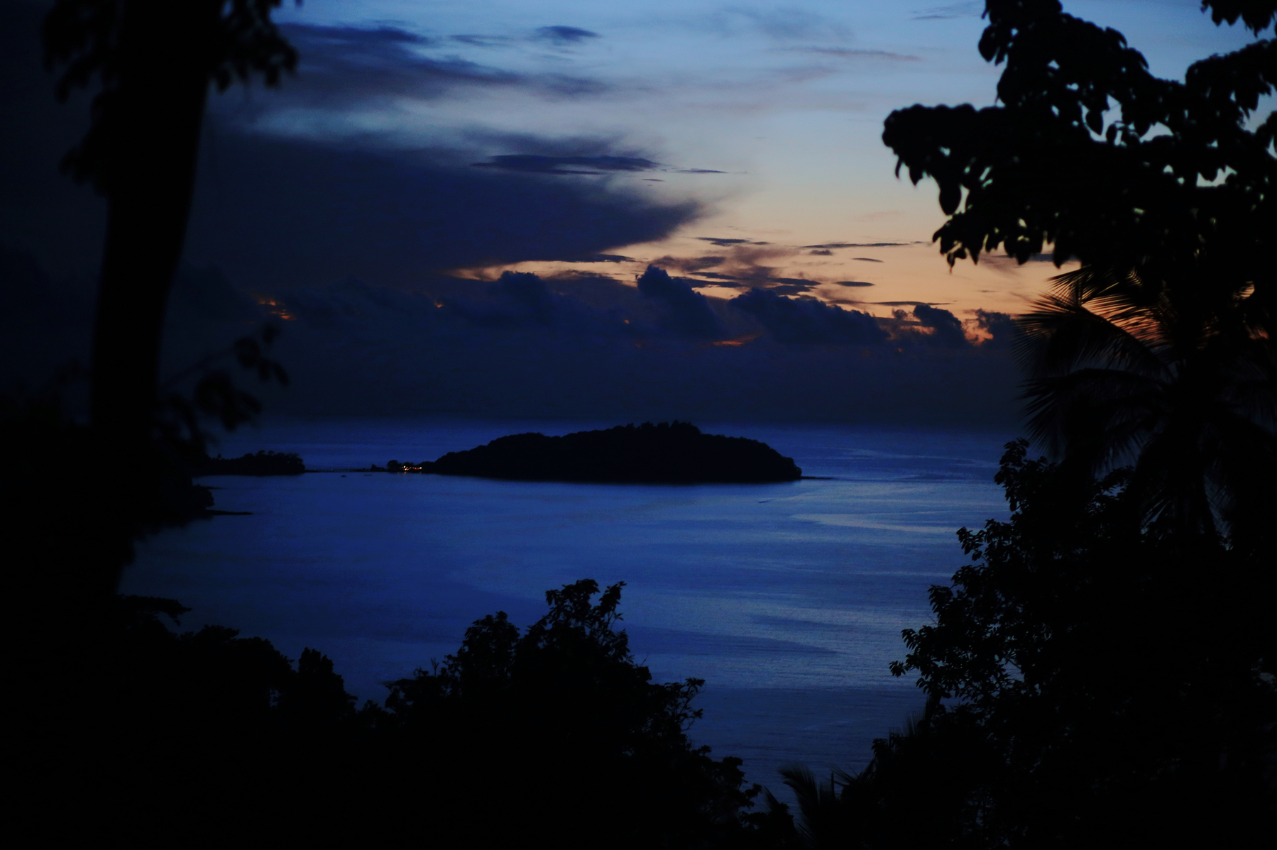 an islet is seen in the middle of the ocean, night time