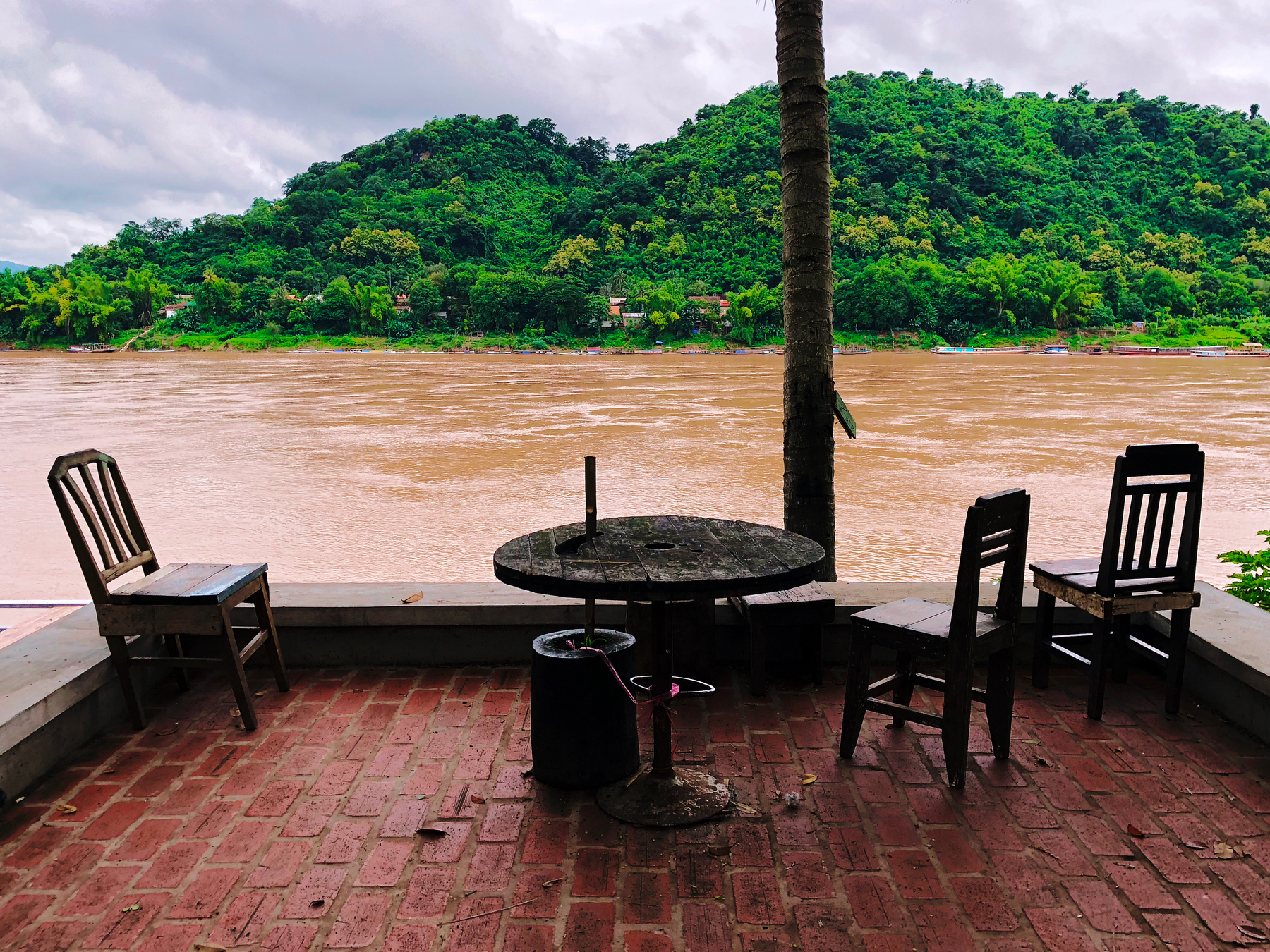 A table and three chair facing a river. 